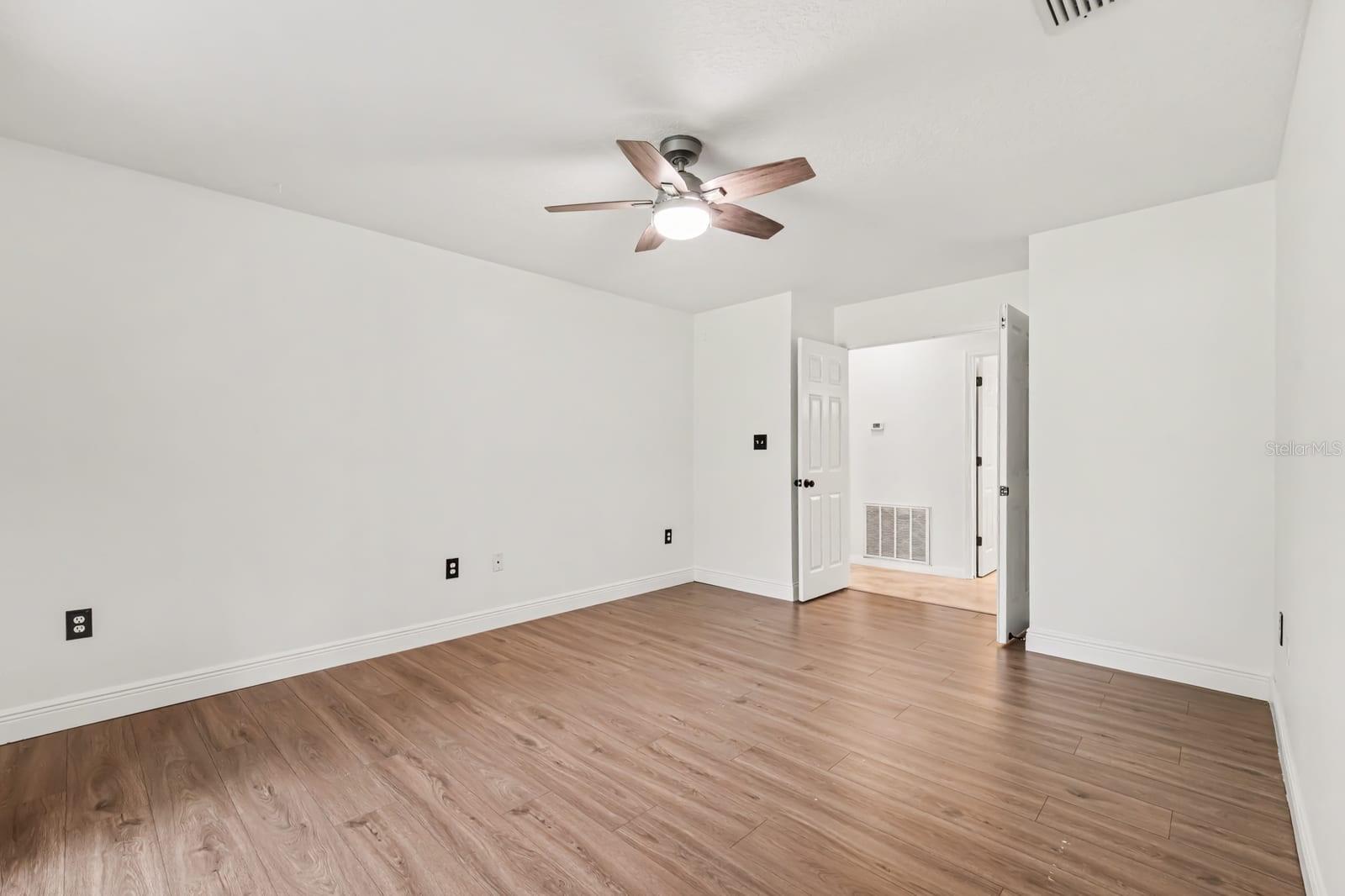 Spacious Bedroom with Ceiling Fan and Neutral Flooring Throughout