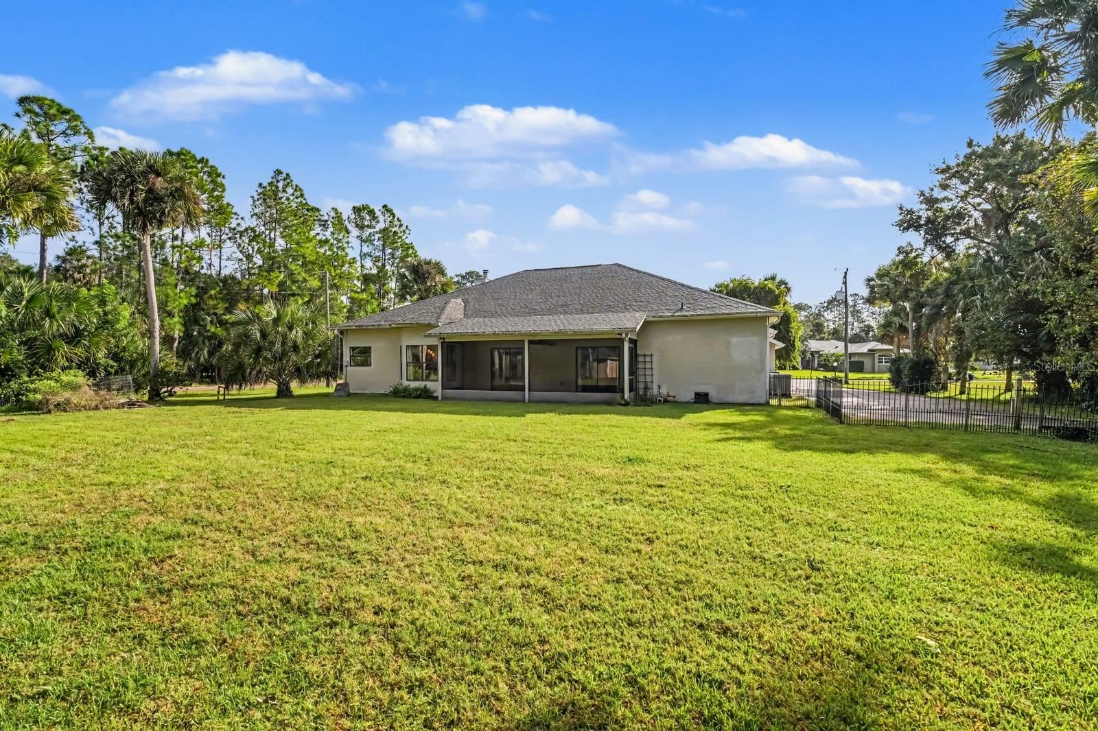 Expansive rear yard with mature landscaping and covered patio overlooking lush grounds