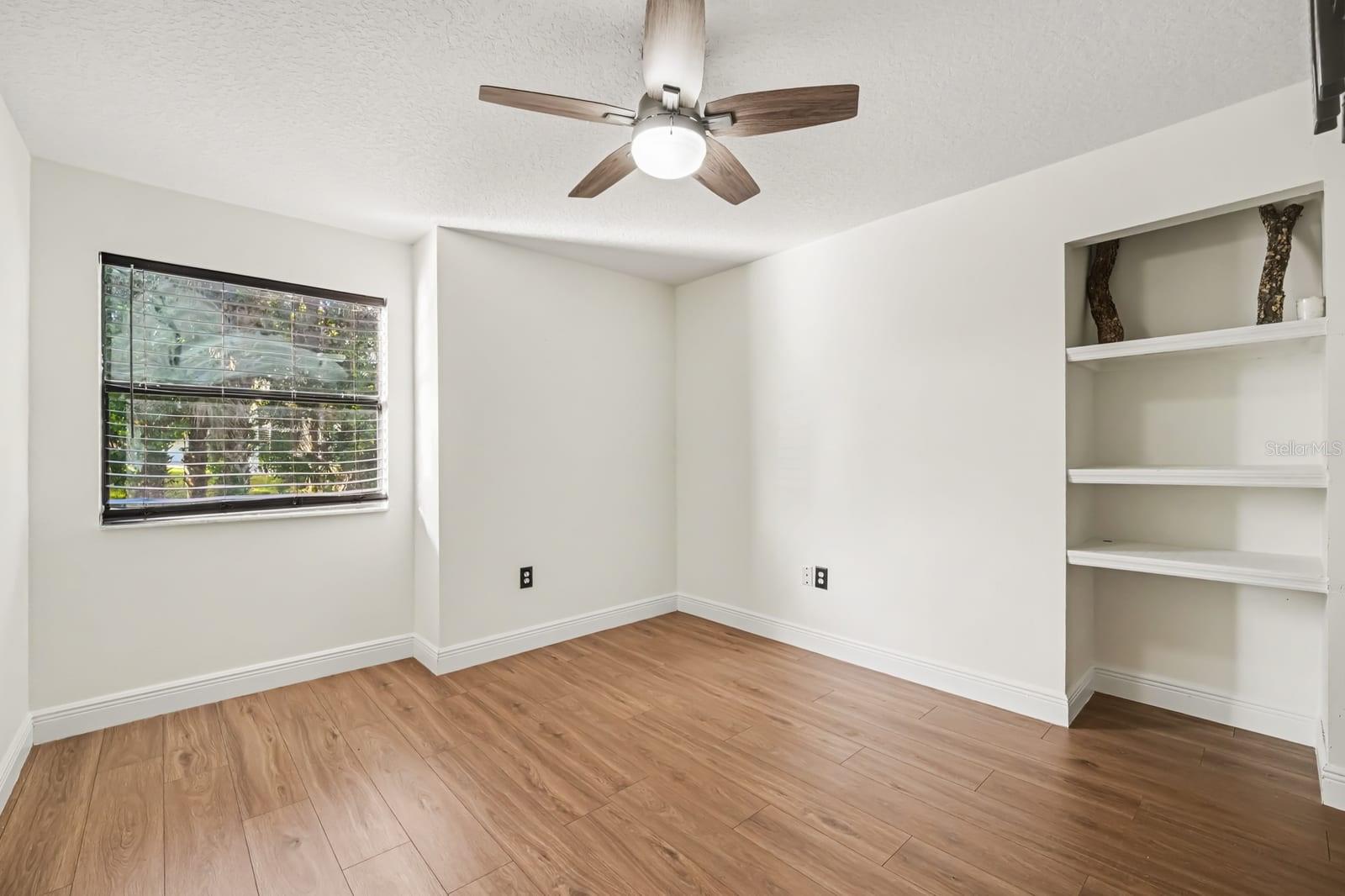 Bright Bedroom with Ceiling Fan, Built-In Shelving, and Window Views