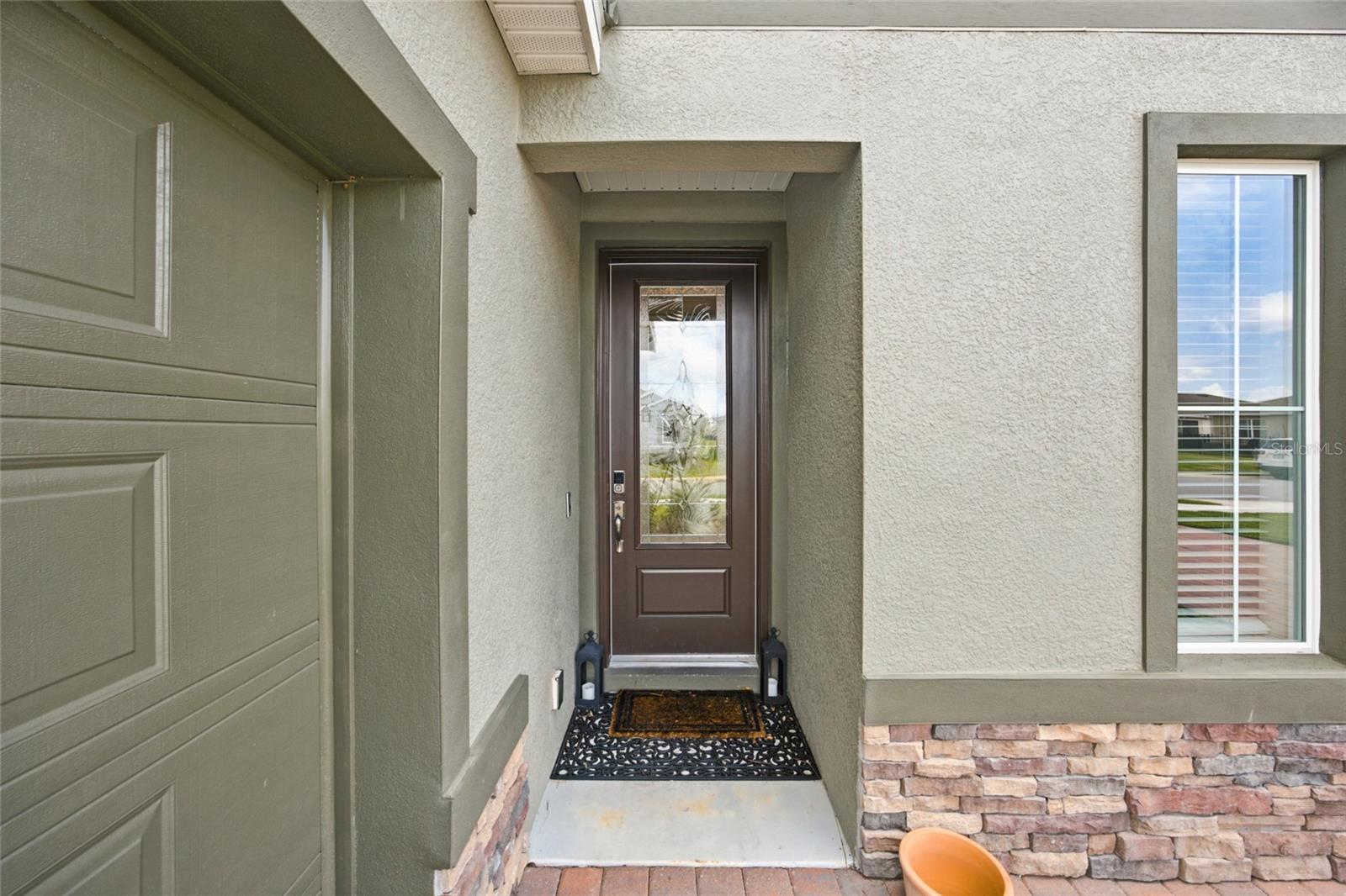 Recessed front entry with decorative glass front door and stone detailing.