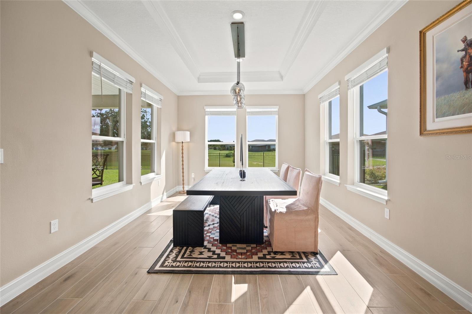 Bright dining room surrounded by windows with views toward the rear green space.