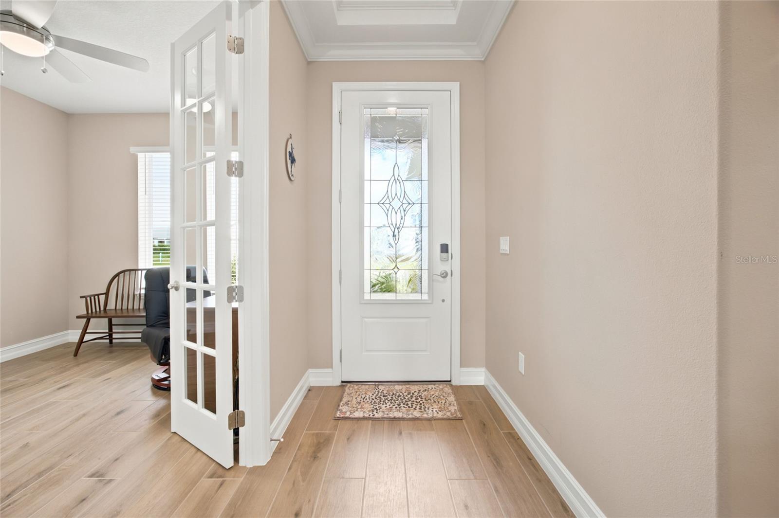 Welcoming foyer with wood-look tile flooring and French doors leading to the office.