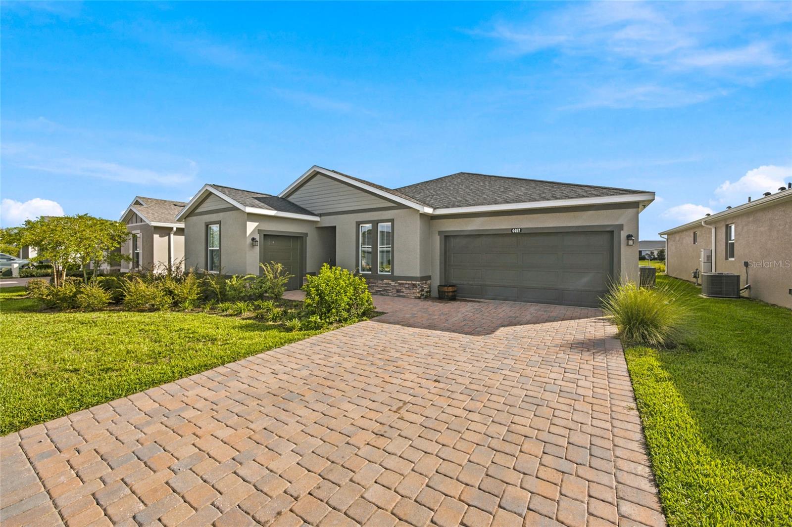 Angled exterior view highlighting the attractive paver driveway and landscaping.