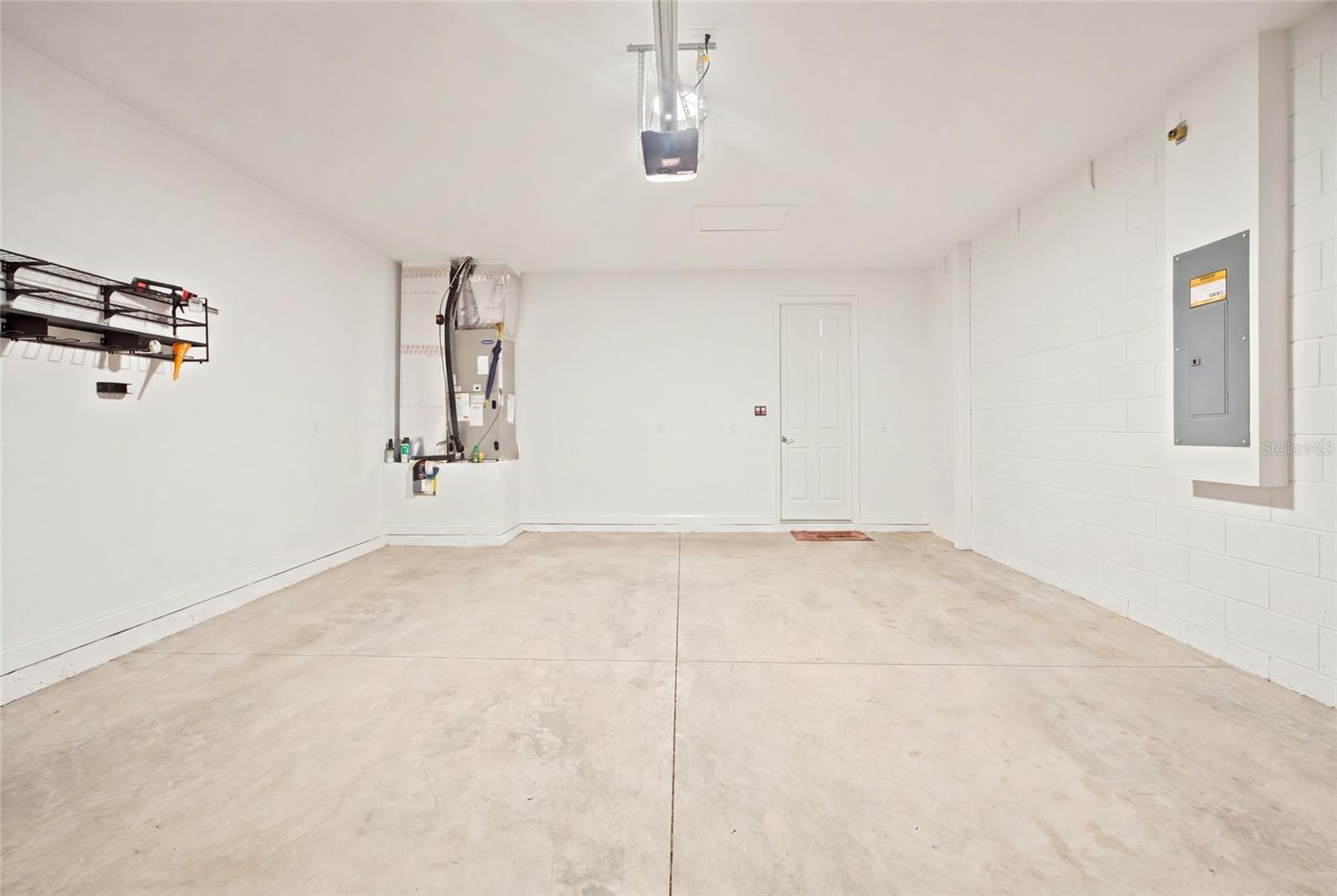 Two-car garage with concrete flooring and overhead storage rack.