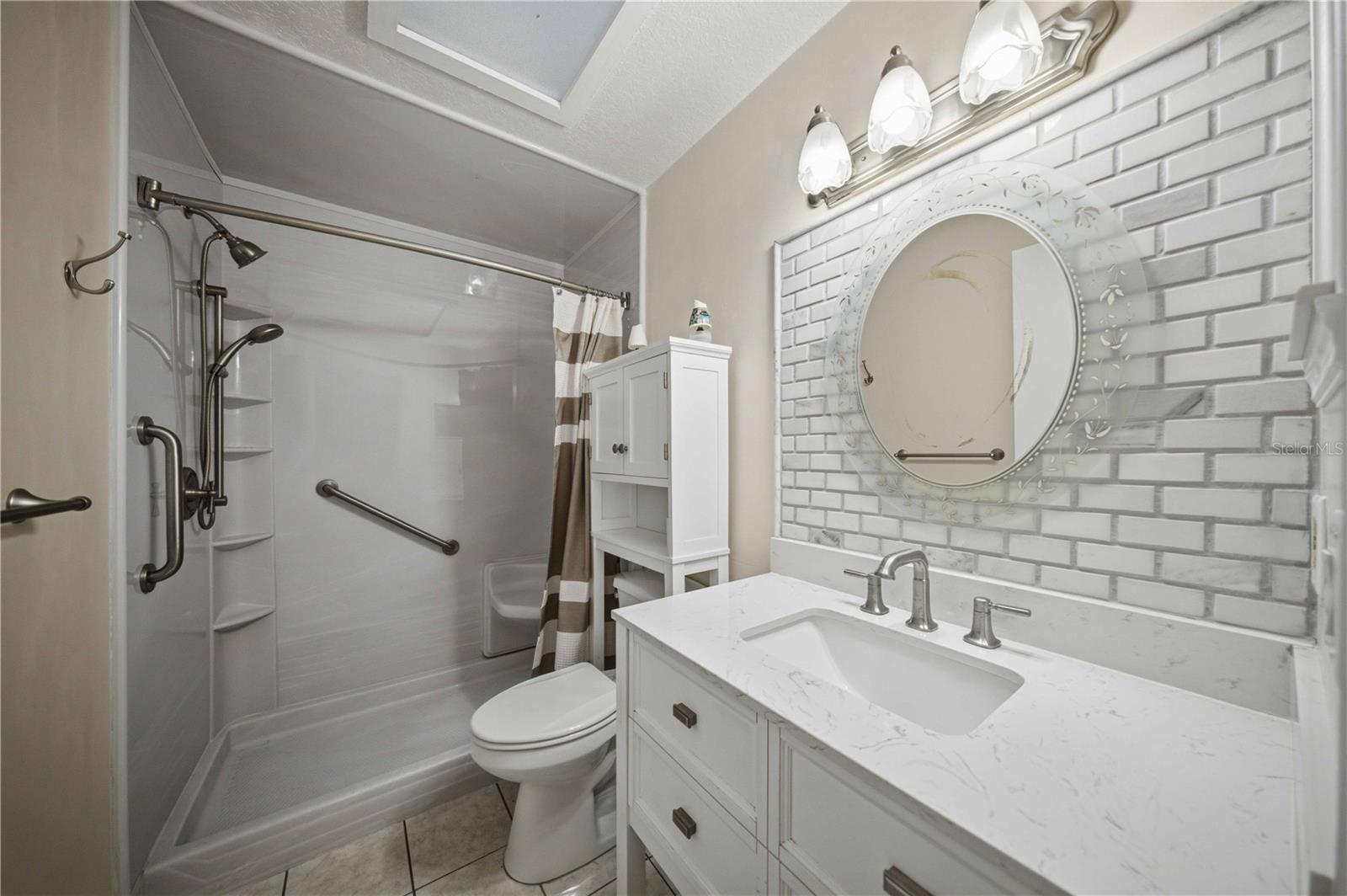 Updated guest bath with tile back splash, new vanity, comfort height toilet, and shower with a bench