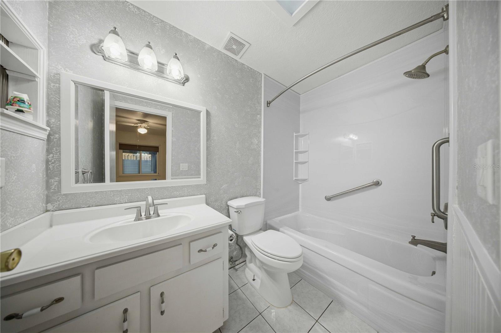 Primary en-suite, with wainscotting, comfort height toilet, and tub/shower combo with grab bars