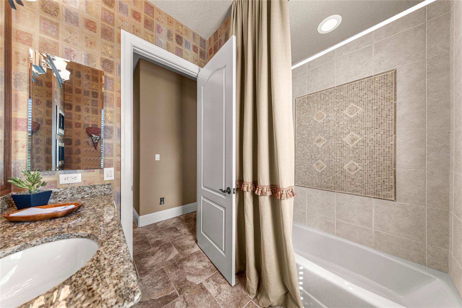 Tub and shower combination with decorative tile surround and accent detailing, offering both style and functionality.
