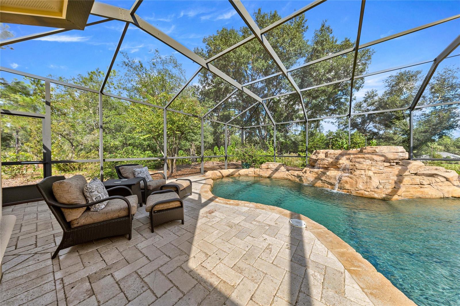 Your private backyard retreat! Custom-designed pool with cascading rock waterfall, natural stone accents, and expansive paver decking.