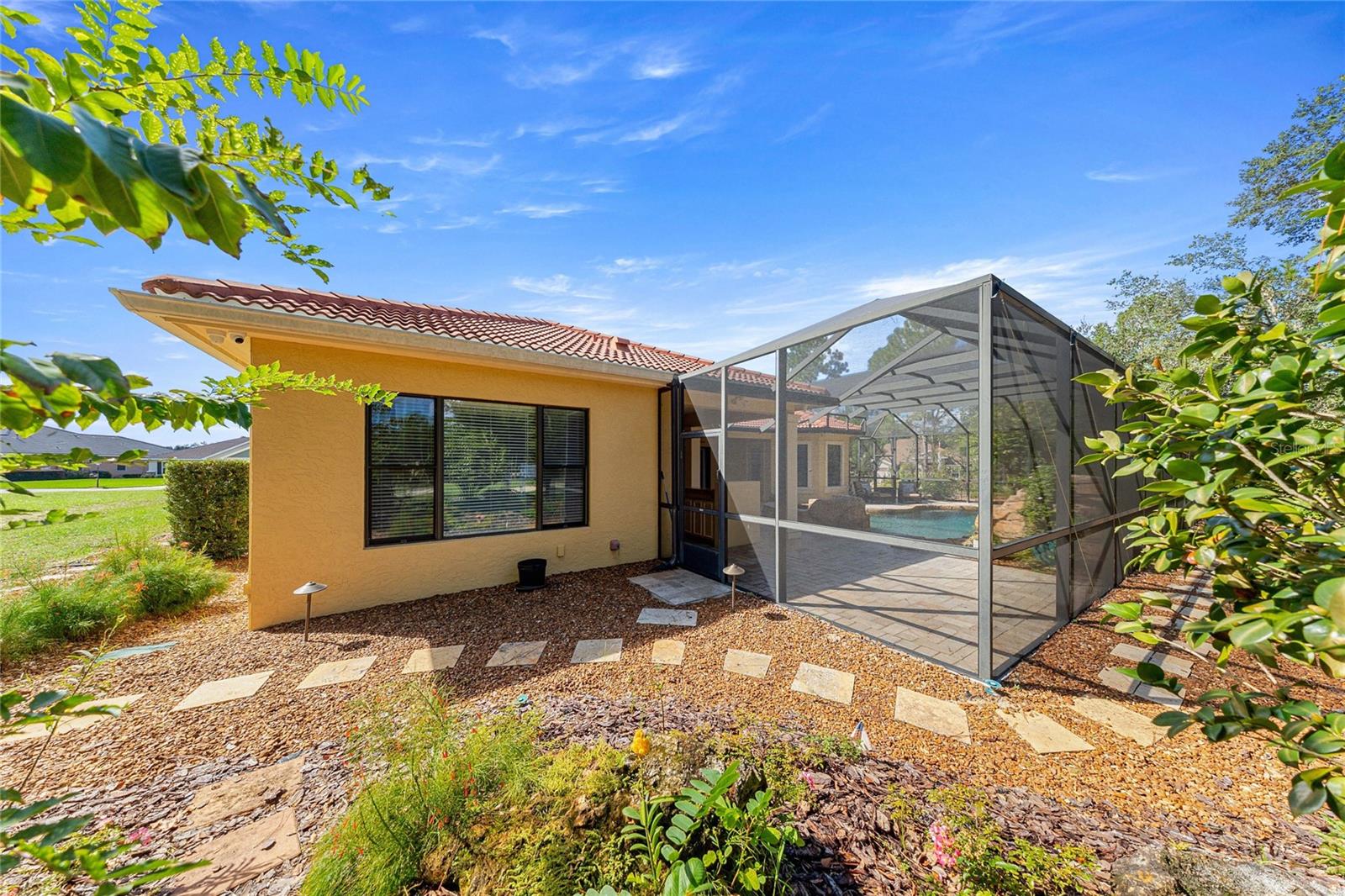 Screened Pool Enclosure  Expansive screened outdoor living area surrounded by natural landscaping.