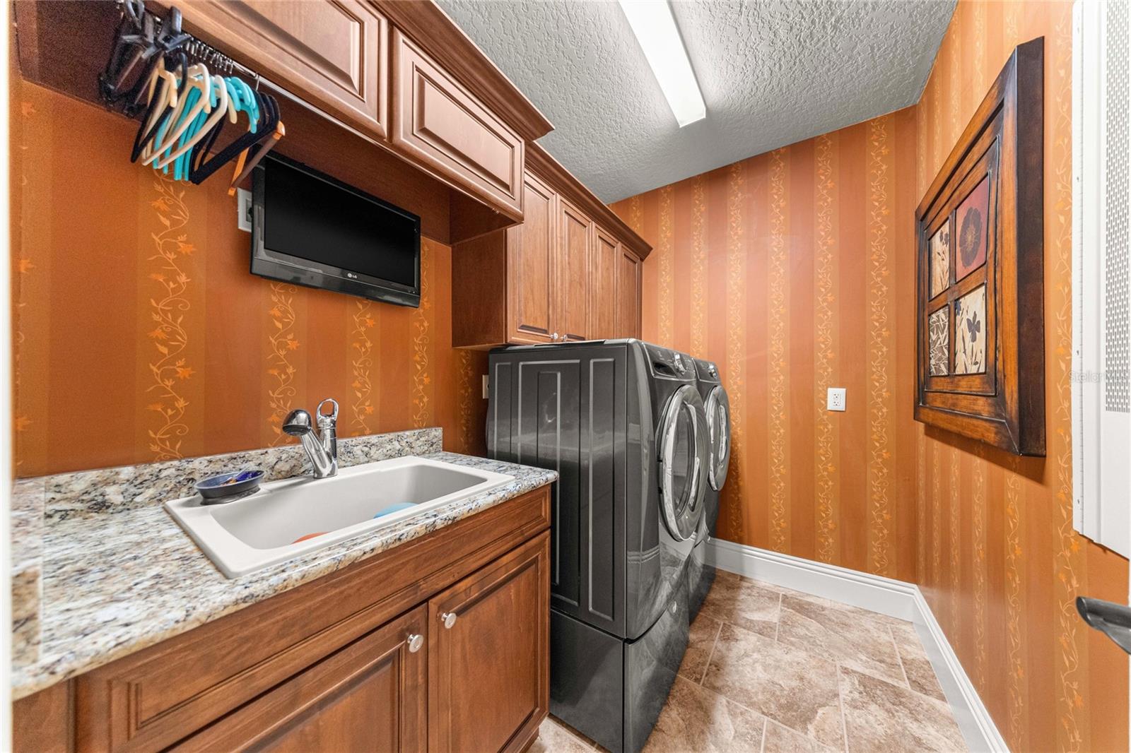 Laundry Room  Built-in wood cabinetry, granite countertop, utility sink, and washer and dryer.