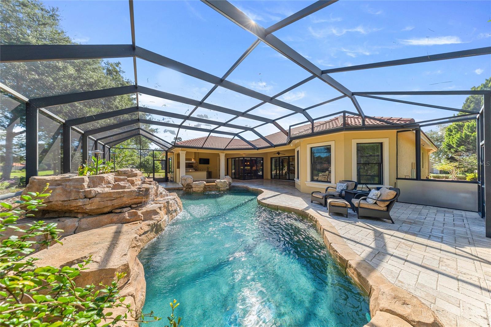Screened Pool Enclosure  Expansive screened outdoor living area surrounded by natural landscaping.