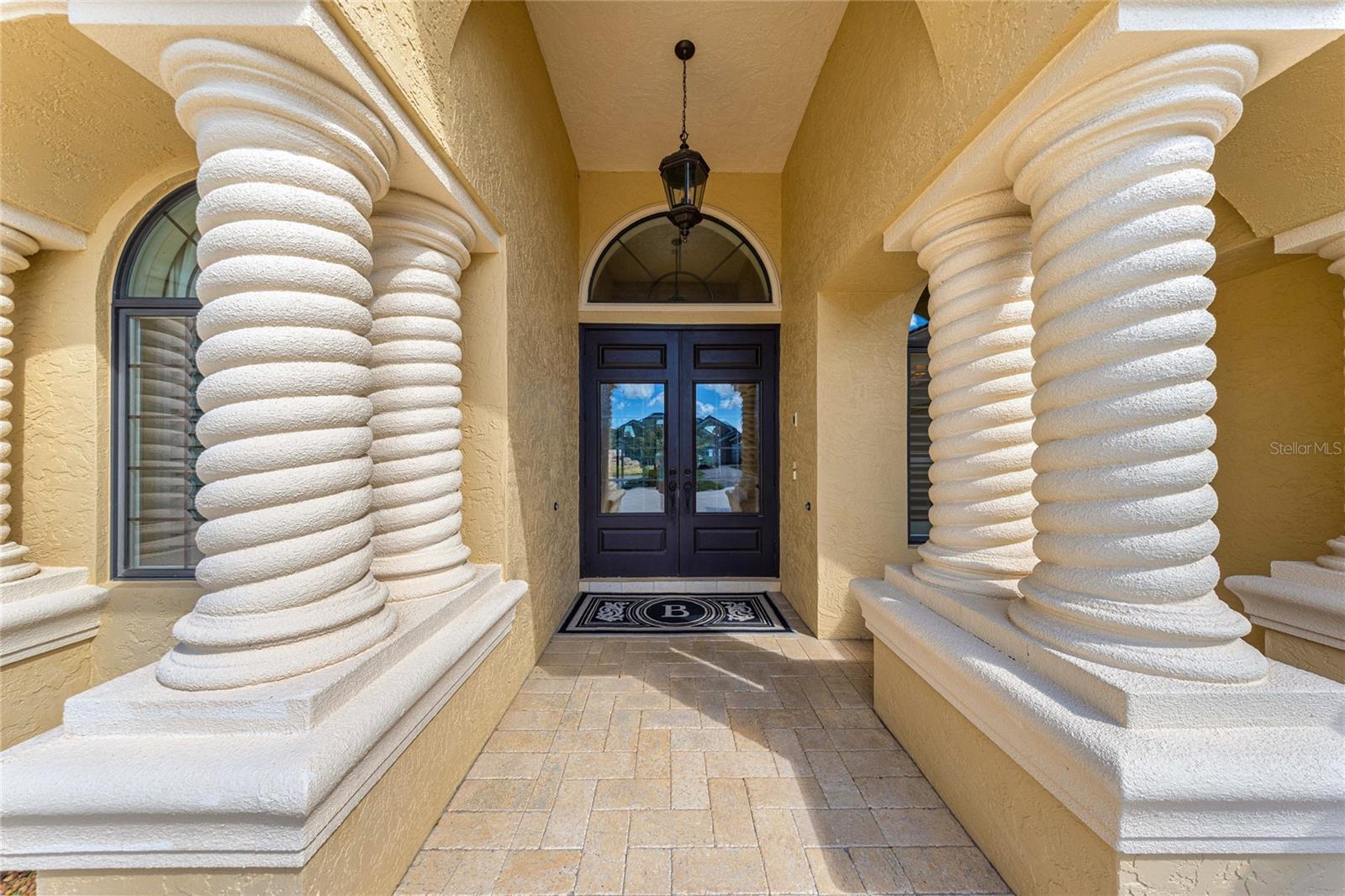 Impressive covered entryway featuring distinctive spiral columns, decorative arches, elegant double doors, and beautiful paver flooring. Impressive covered entryway featuring distinctive spiral columns, decorative arches, elegant double doors, and beautiful paver flooring.