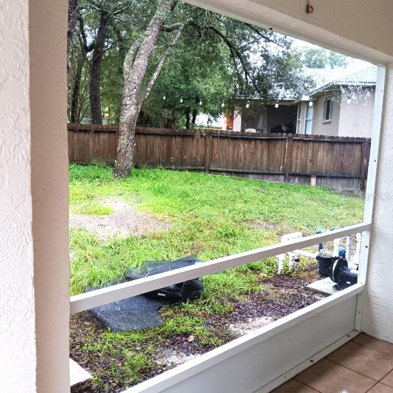 Looking out sliding doors from dining area across lanai to fenced back yard.