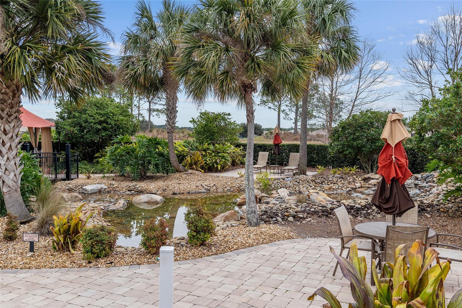 Tranquil water feature at The Lodge at Candler Hills, surrounded by lush tropical landscaping, natural stone accents, and inviting outdoor seating areascreating a peaceful retreat to relax and enjoy the beautiful surroundings.