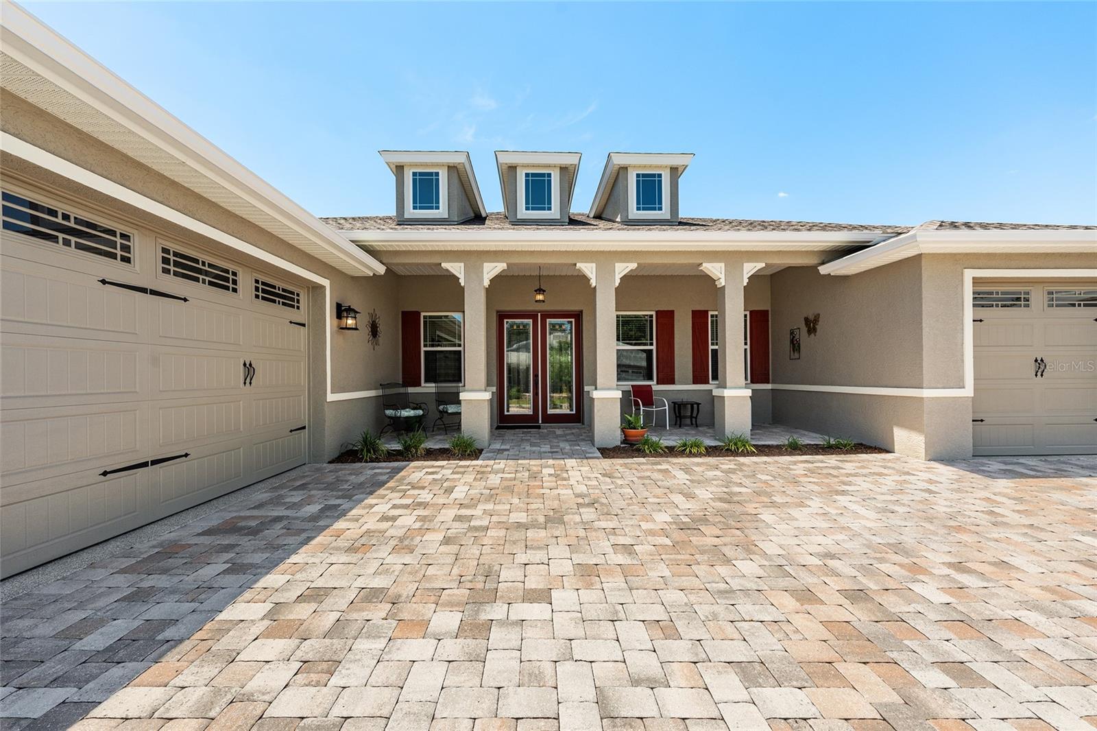 Beautiful 2021 Aberdeen model offering exceptional curb appeal with an expansive covered front porch, elegant leaded-glass double entry doors, attractive paver driveway, and professionally landscaped grounds that create a warm and welcoming first impression.