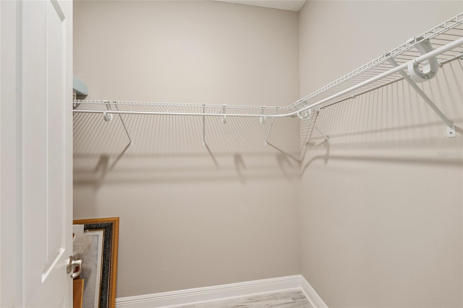 Second primary suite's spacious walk-in closet features wraparound shelving and ample hanging space, providing practical storage and organization.