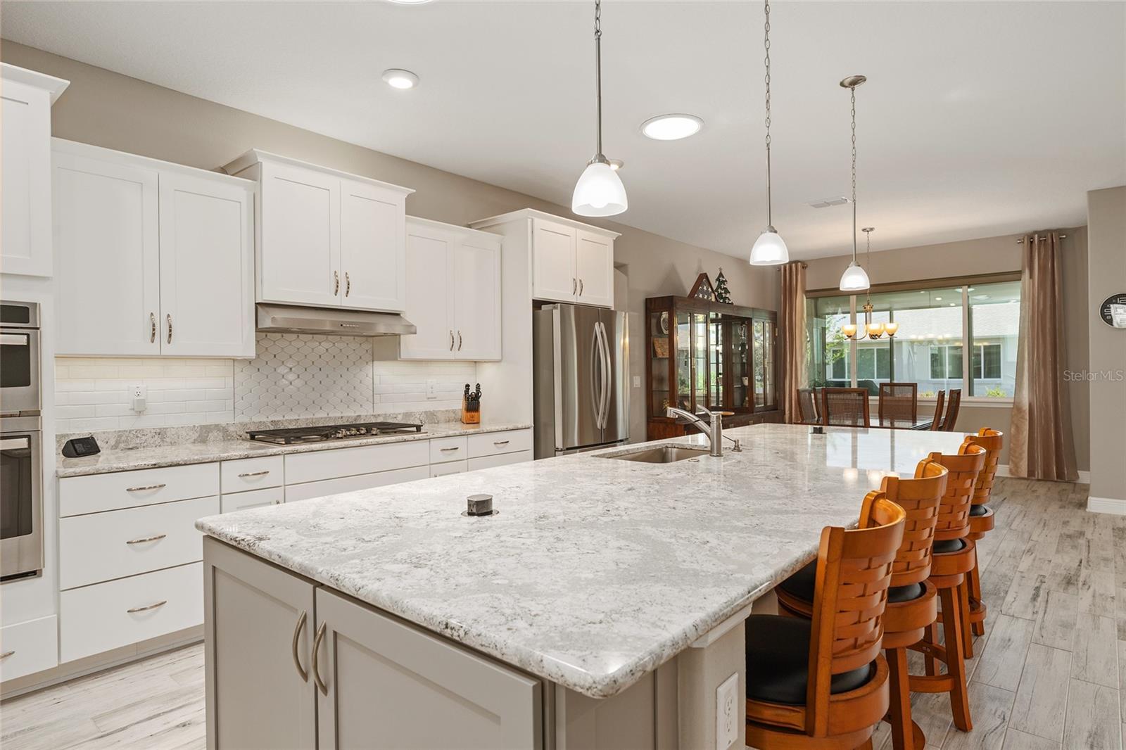 Expansive Cambria quartz kitchen island featuring two concealed pop-up outlets, a built-in soap dispenser, additional end cabinetry for storage, and generous seatingcombining style and everyday convenience.