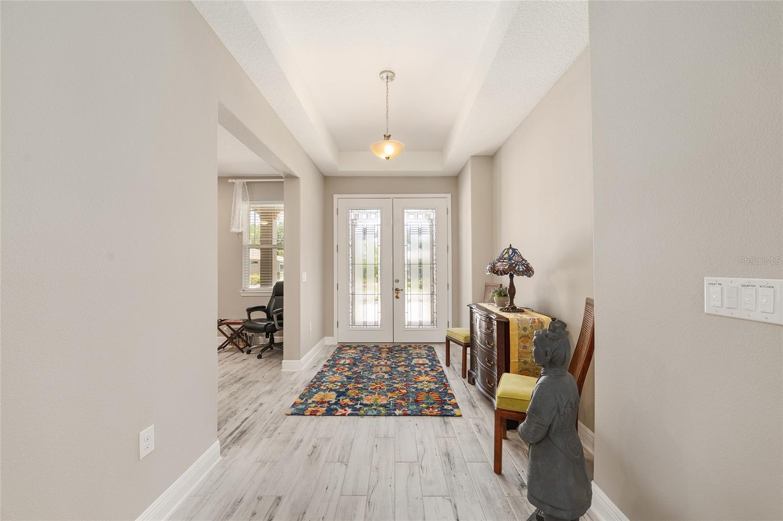 Spacious foyer with an elegant tray ceiling and a welcoming layout, offering a glimpse into the versatile flex roomperfect for a home office, sitting room, or quiet retreat.
