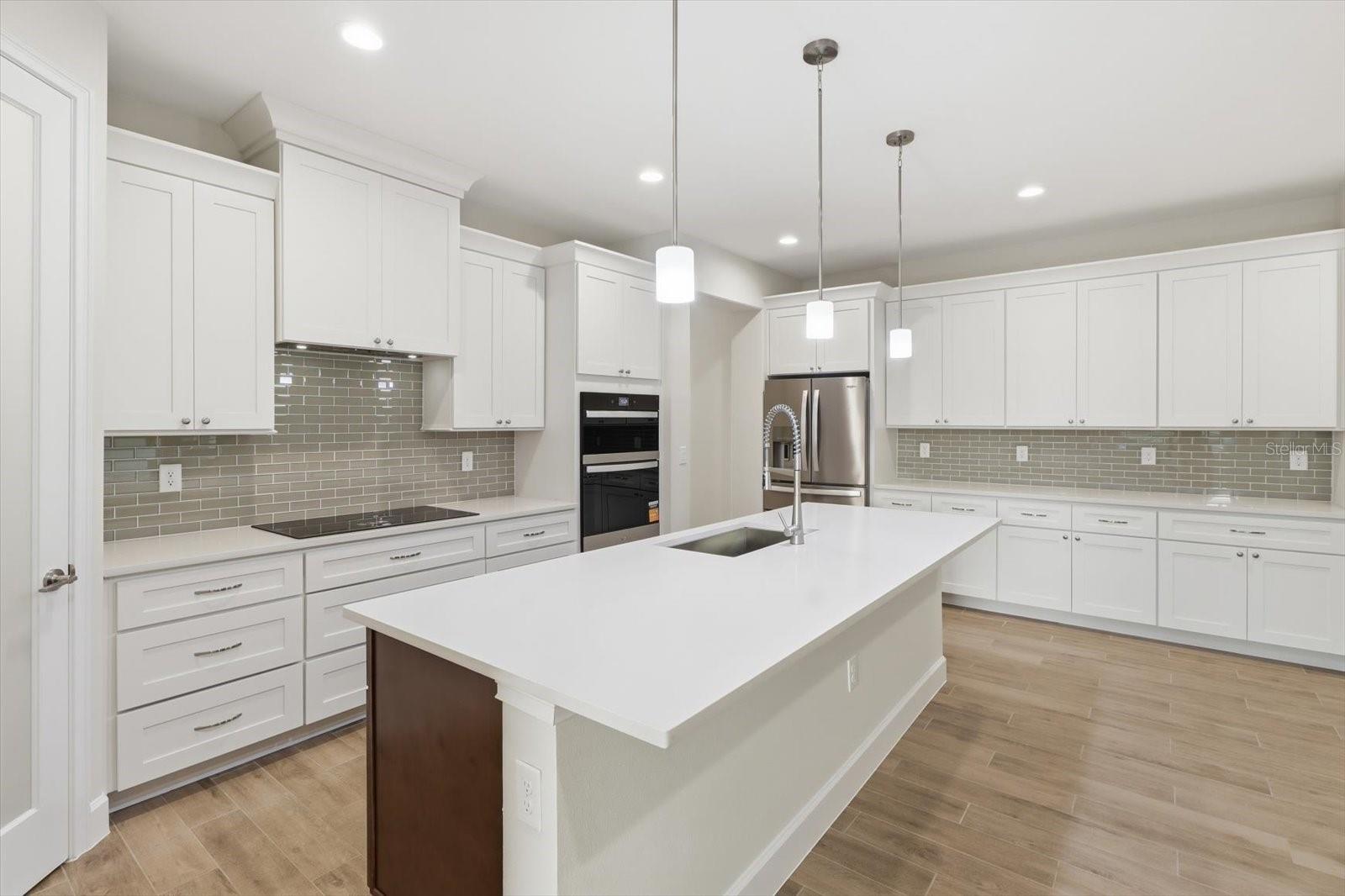 The chefs kitchen features an oversized quartz island, walk in pantry, crown molding and upgraded 4 door refridgerator. The chefs kitchen features an oversized quartz island, walk in pantry, crown molding and upgraded 4 door refridgerator.
