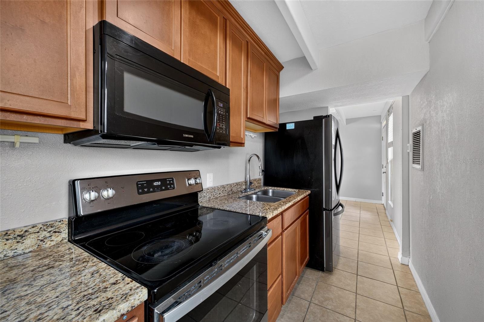 Granite Countertops. Stainless steel / black kitchen appliances including a built in microwave.