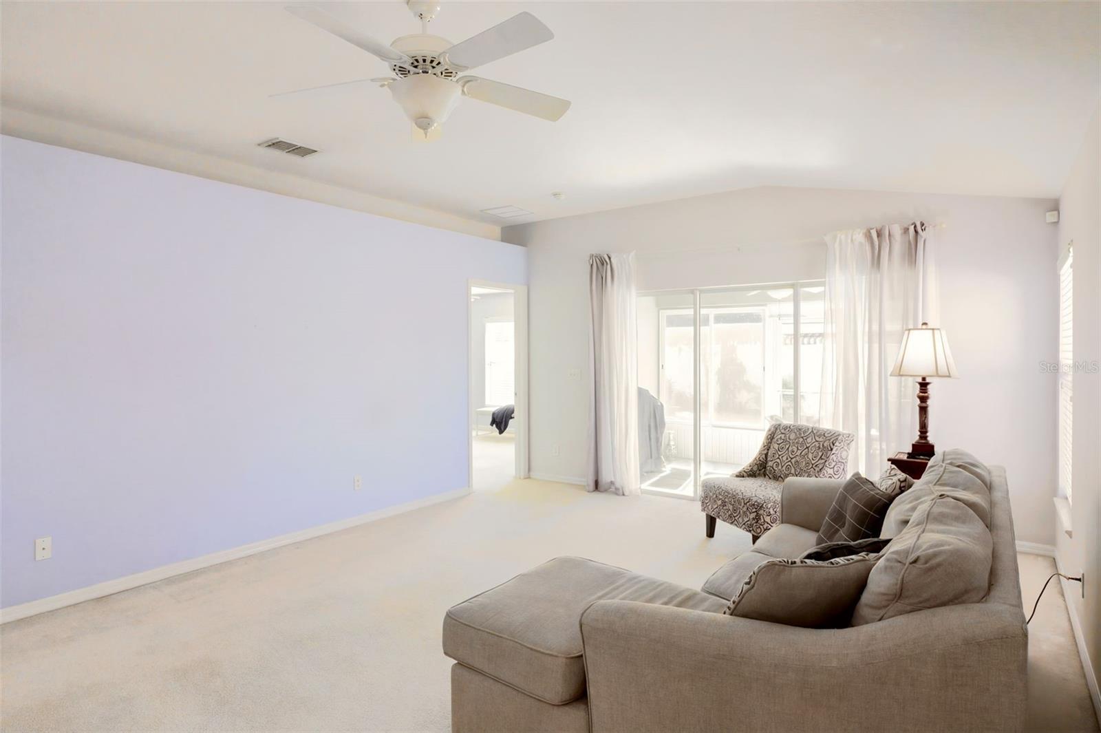 Triple sliding glass doors leading to the Florida room, where tranquil garden views create a peaceful setting.