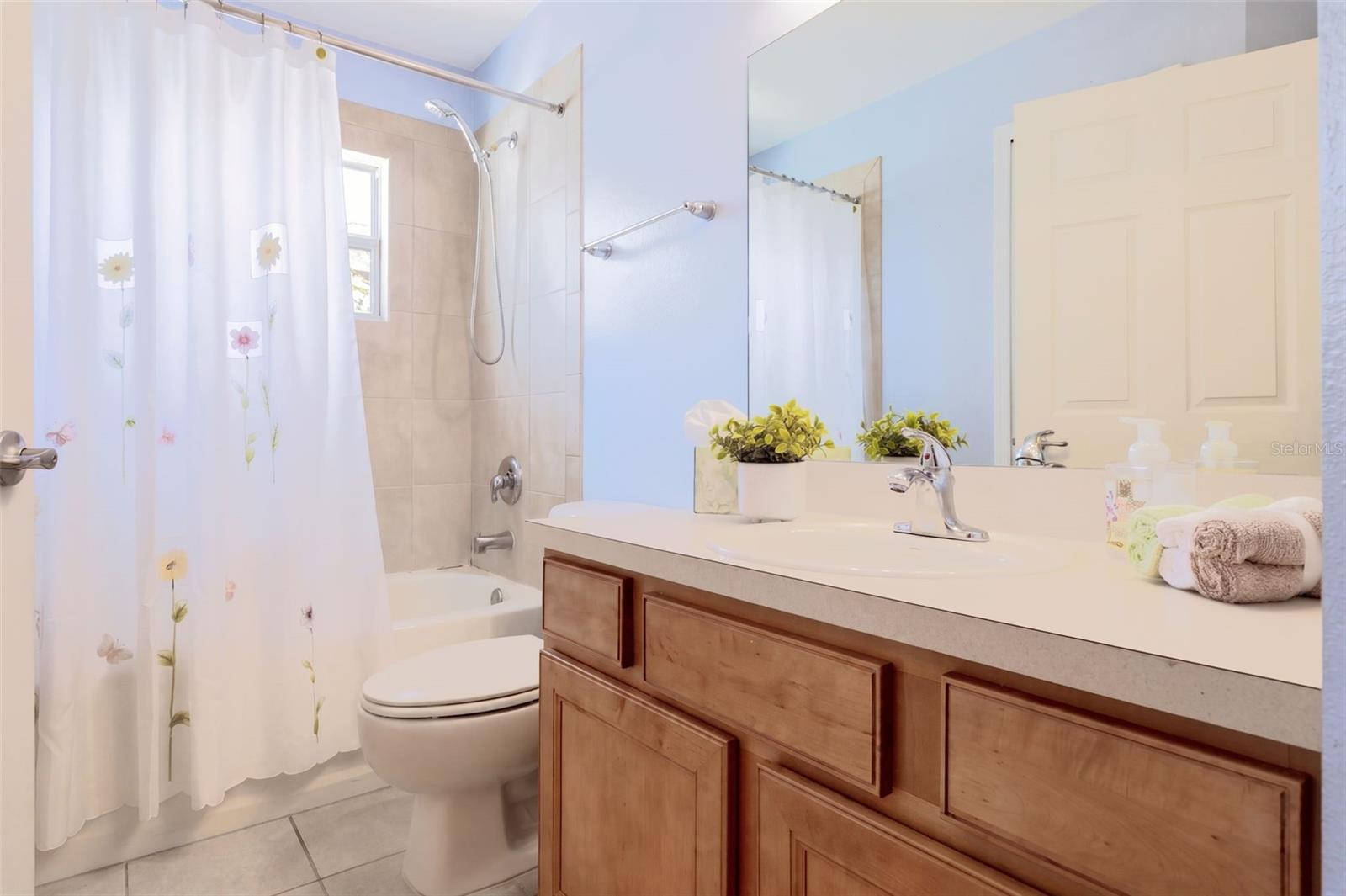 Guest Bathroom with maple wood vanity and tub/shower unit