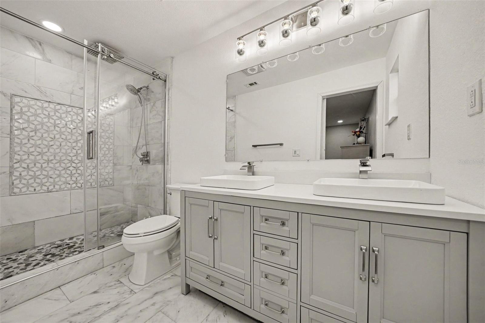 Primary Bath w/Marble tiled walk-in shower, marble tiled flooring and vanity w/ double sinks