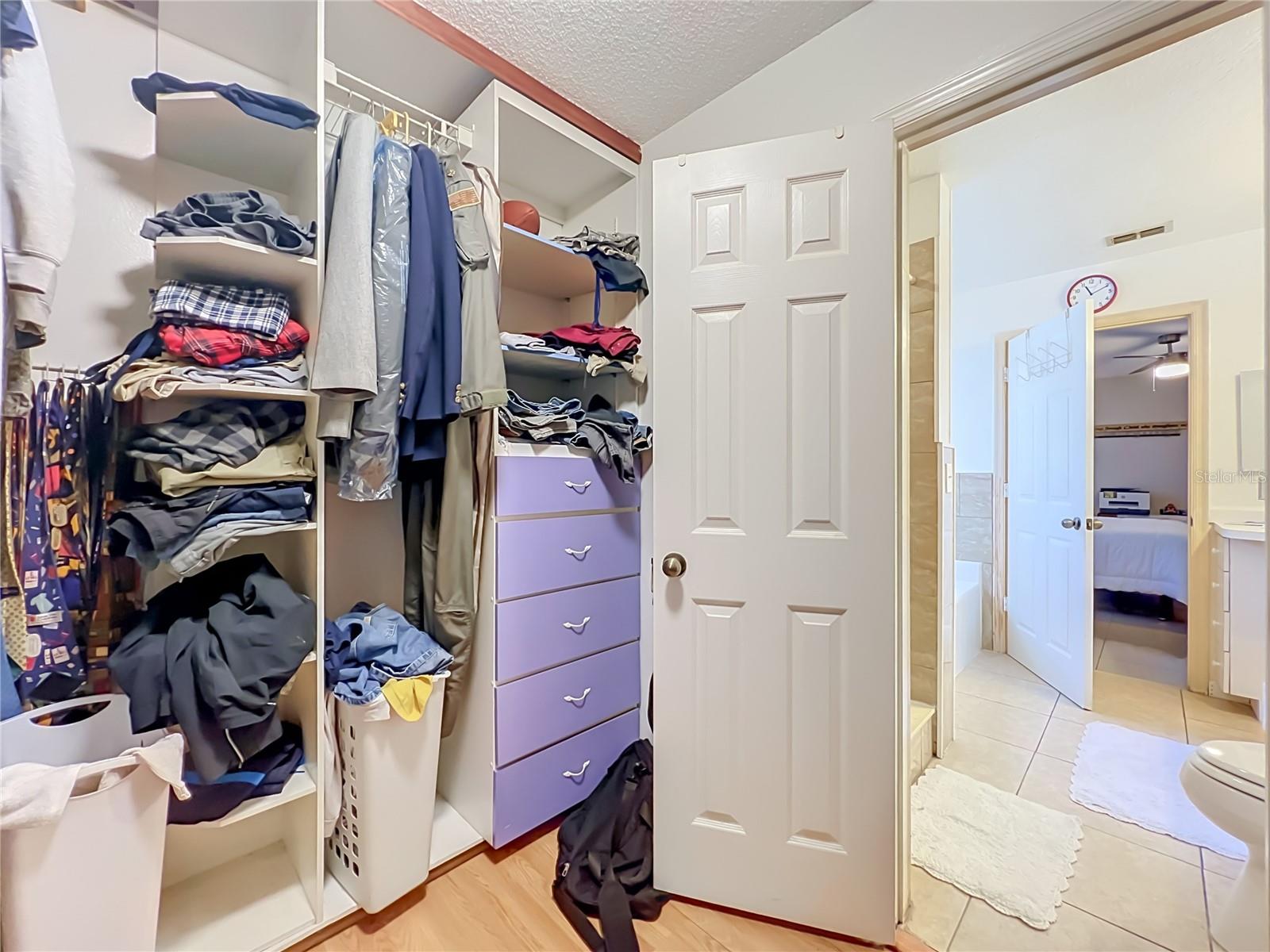 Wood floors and built in drawers and shelving in the large Primary walk in closet