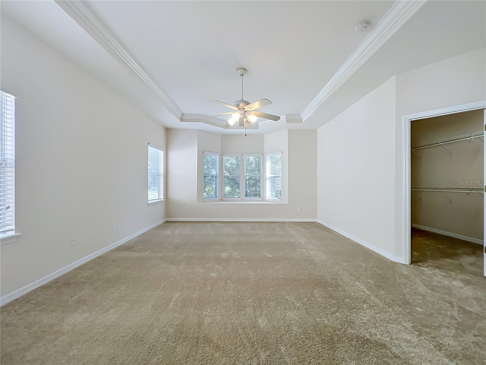 Primary bedroom features window seat, ceiling fan, tray ceiling, and large walk-in closet