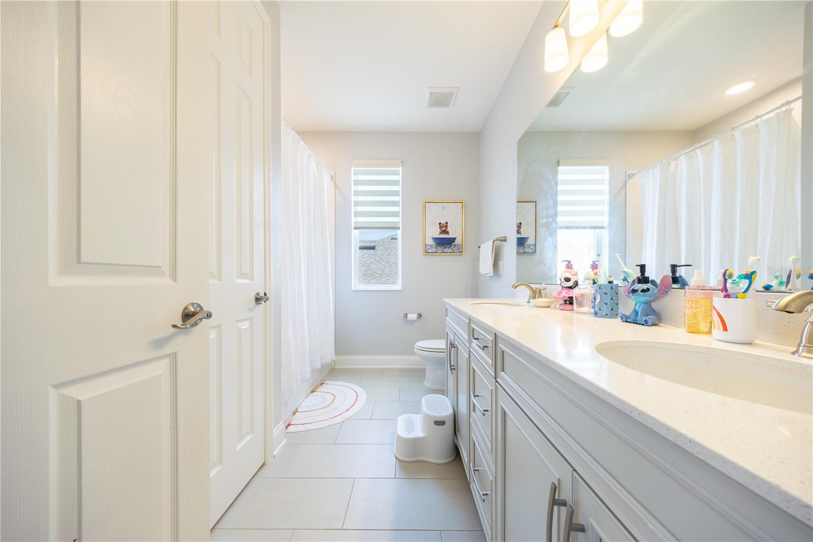 Well-appointed bathroom with a dual-sink vanity, ample storage, and a tub-shower combination.