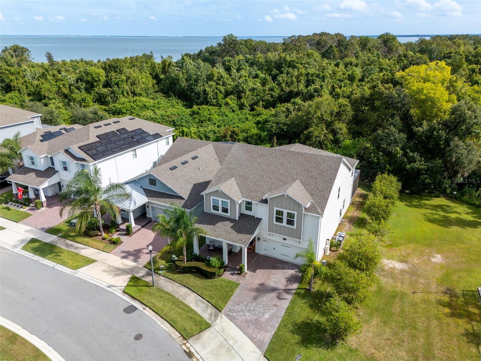 Aerial view showcasing the homes conservation backdrop, no rear neighbors, and the lake beyond.