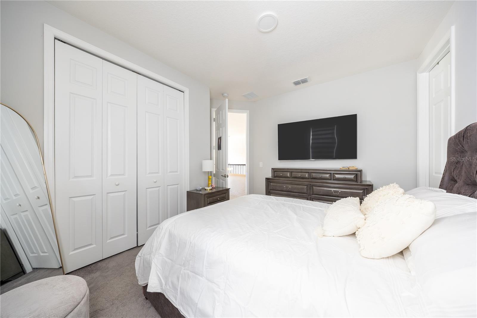 Comfortable bedroom with a spacious closet, soft carpeting, and a refined neutral palette.