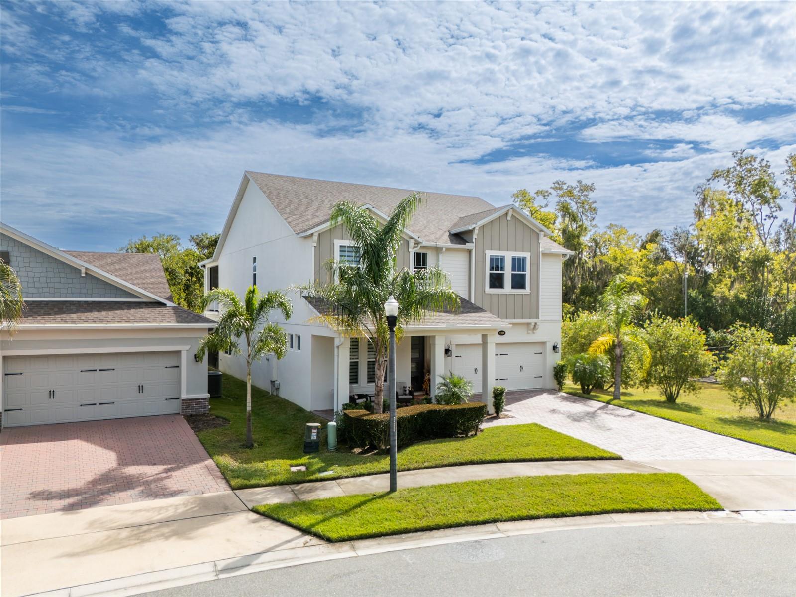 Elevated front view showcasing elegant curb appeal, tropical landscaping, and a two-car garage.