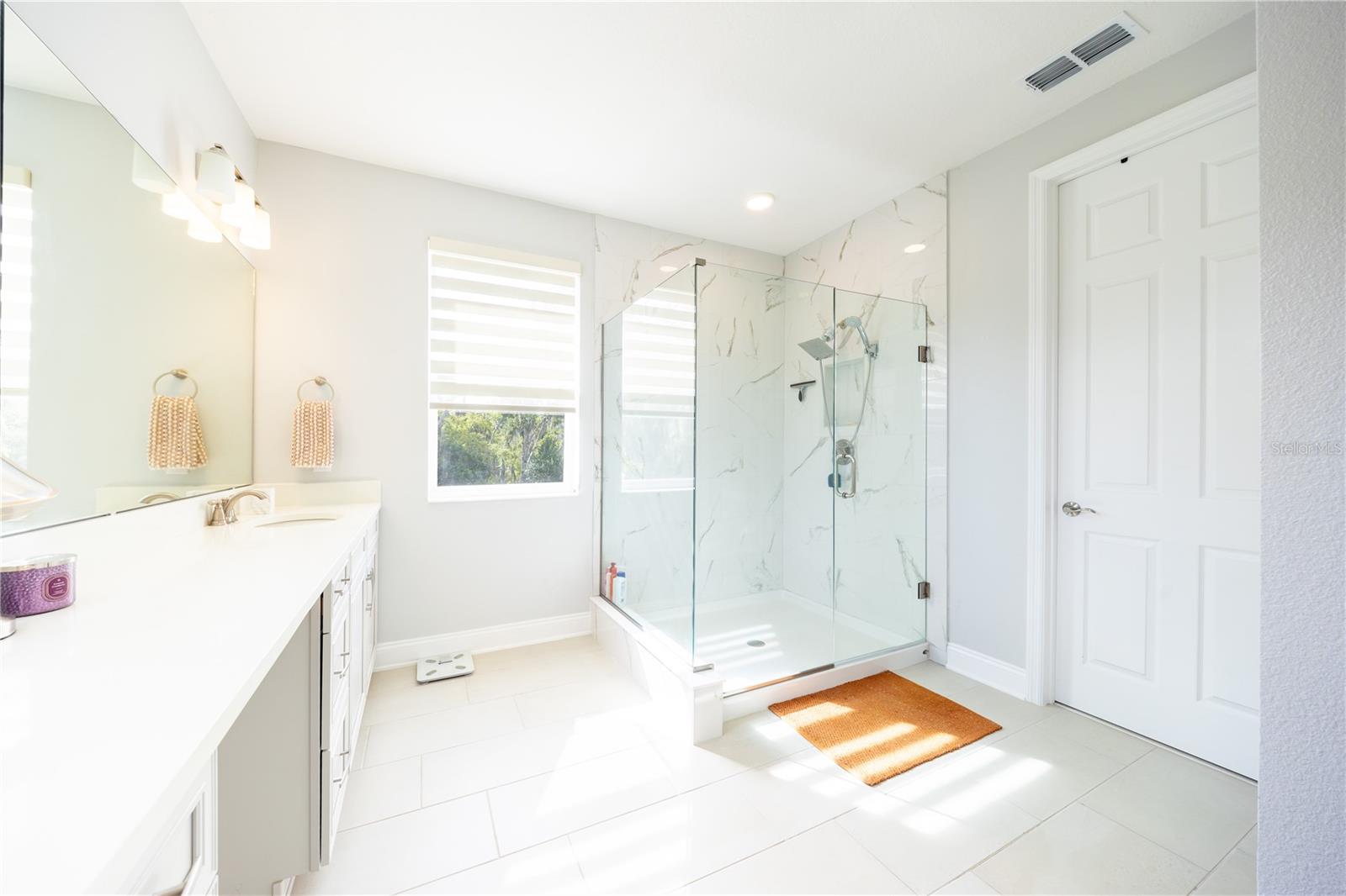 Refined primary bathroom with a frameless glass shower and marble-look tile finishes.