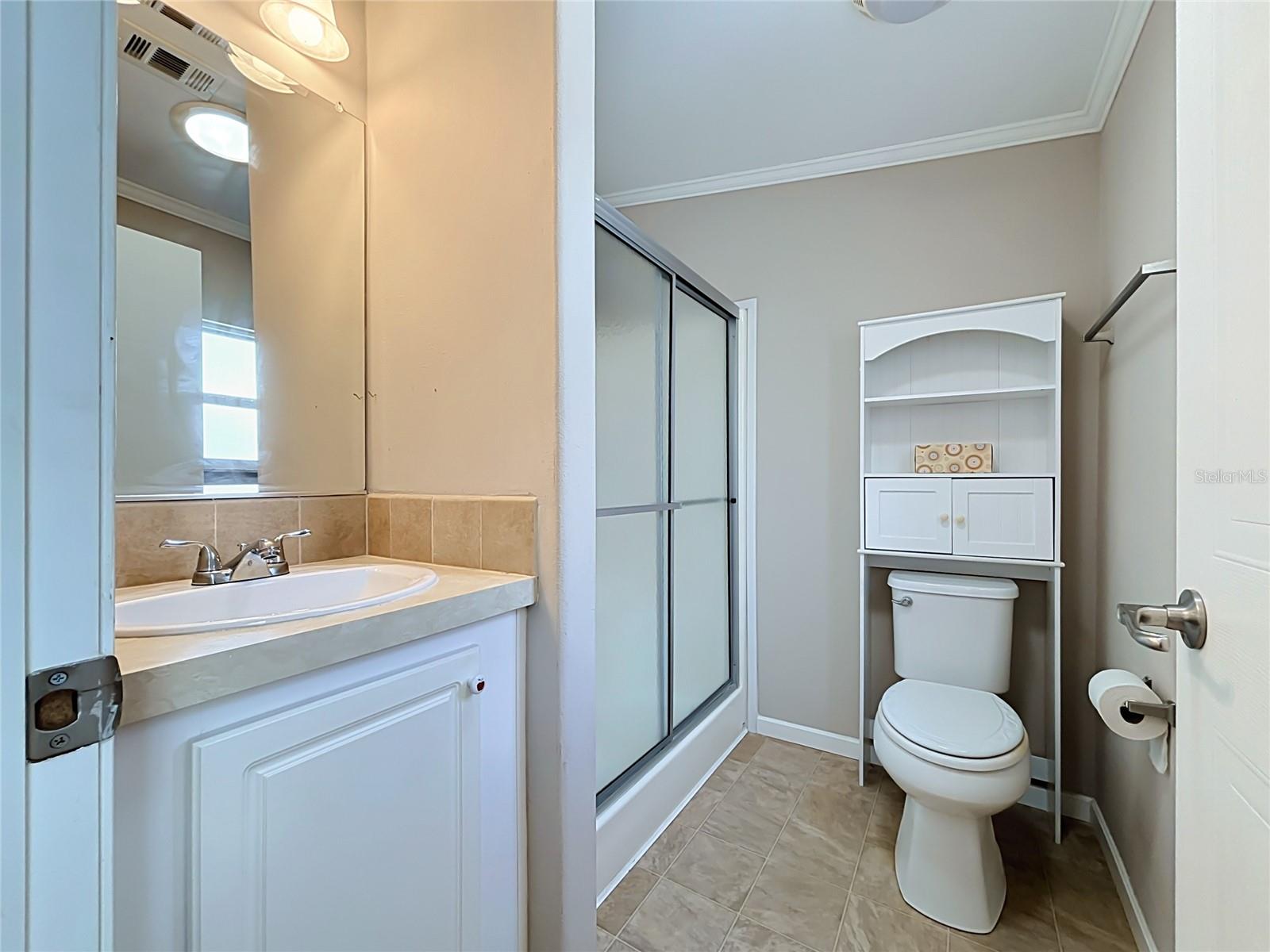 Primary bathroom has walk-in shower and skylight tube allowing natural light to pass through