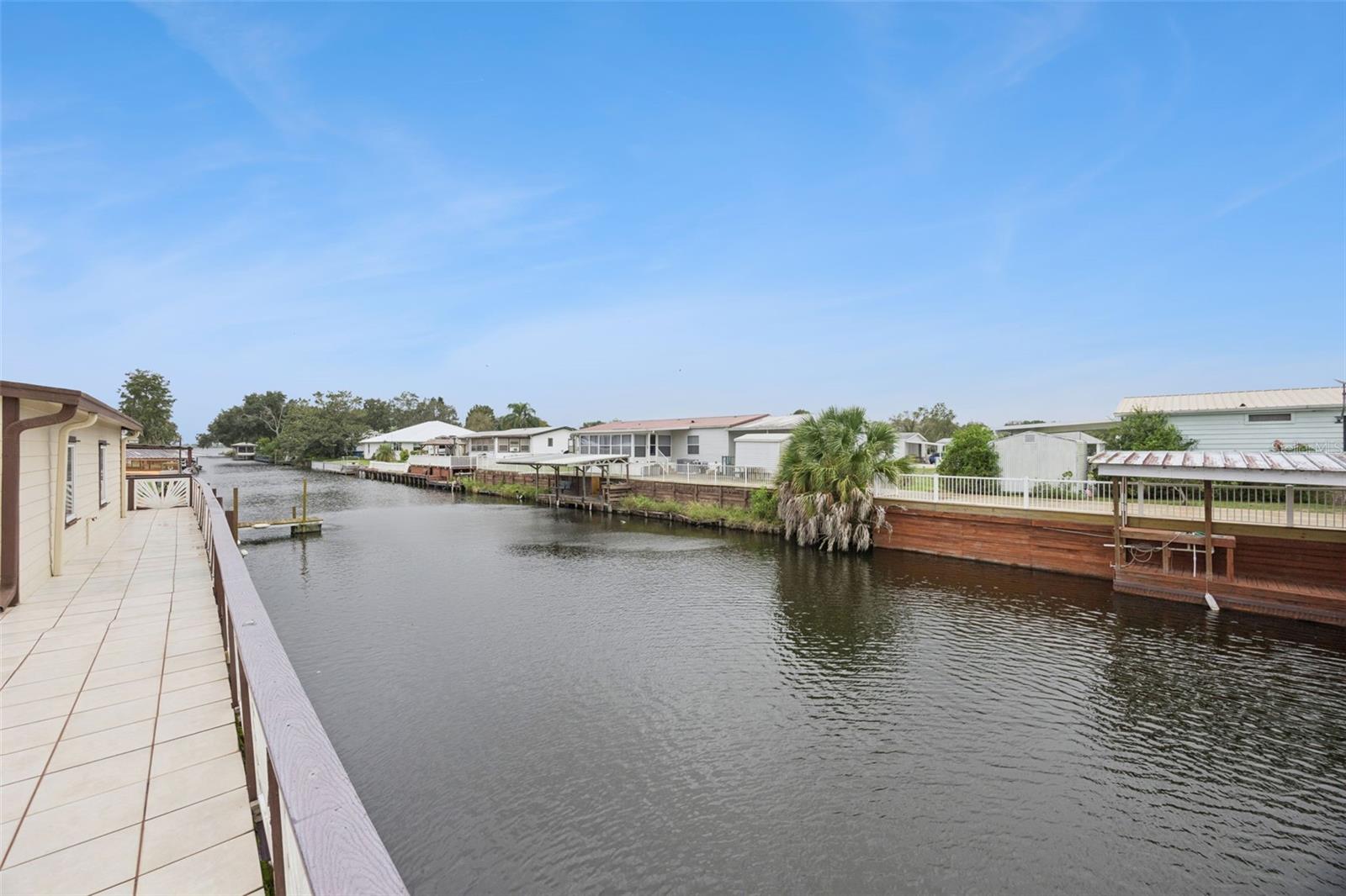 Canal Waterfront Panorama: Sweeping view along the tiled rear patio deck showcasing the navigable canal frontage.