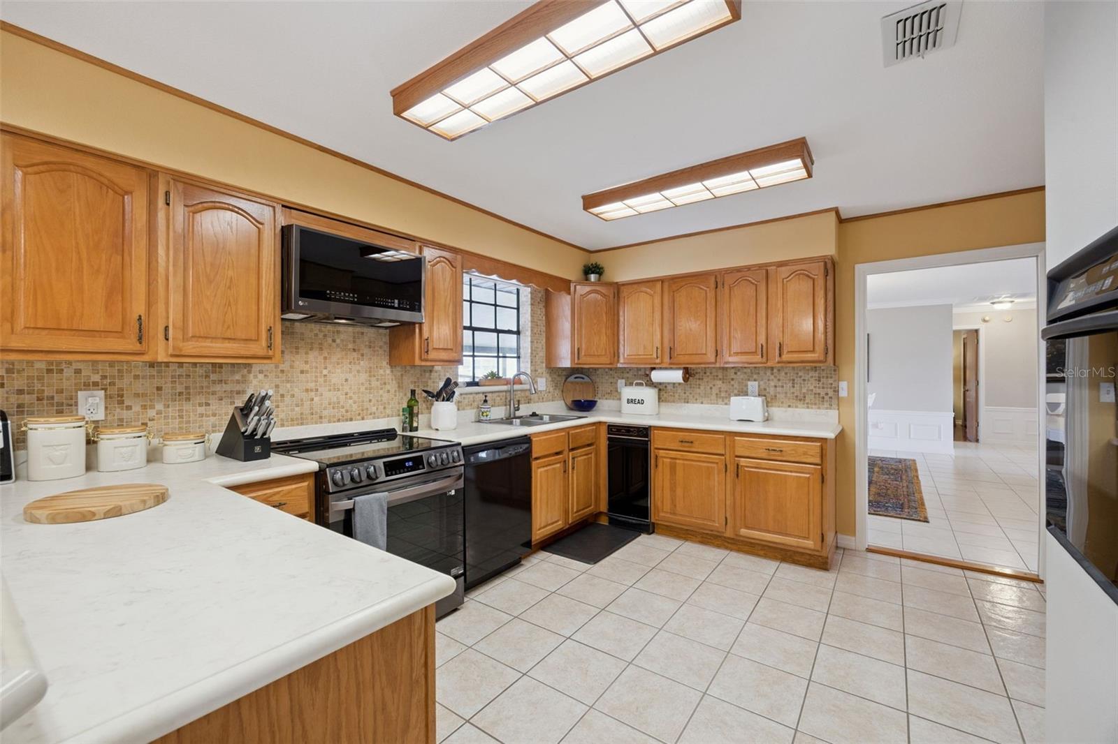 Kitchen Overview: Full kitchen perspective detailing abundant cabinet storage, counter workspace, mosaic tile backsplash, and built-in microwave unit.