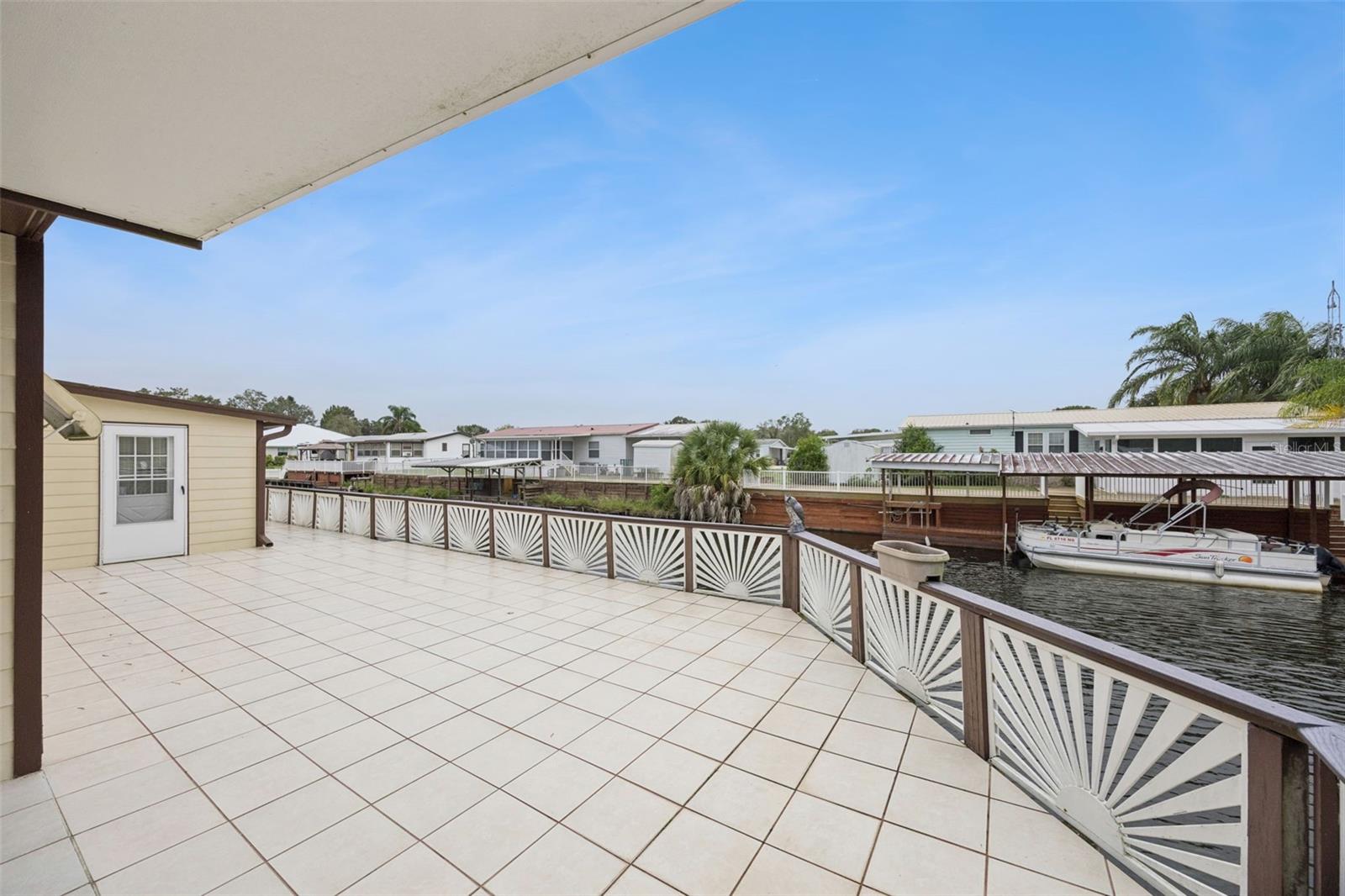Open Waterfront Decking: Wide open tiled deck area bordered by decorative railing directly along the water's edge.