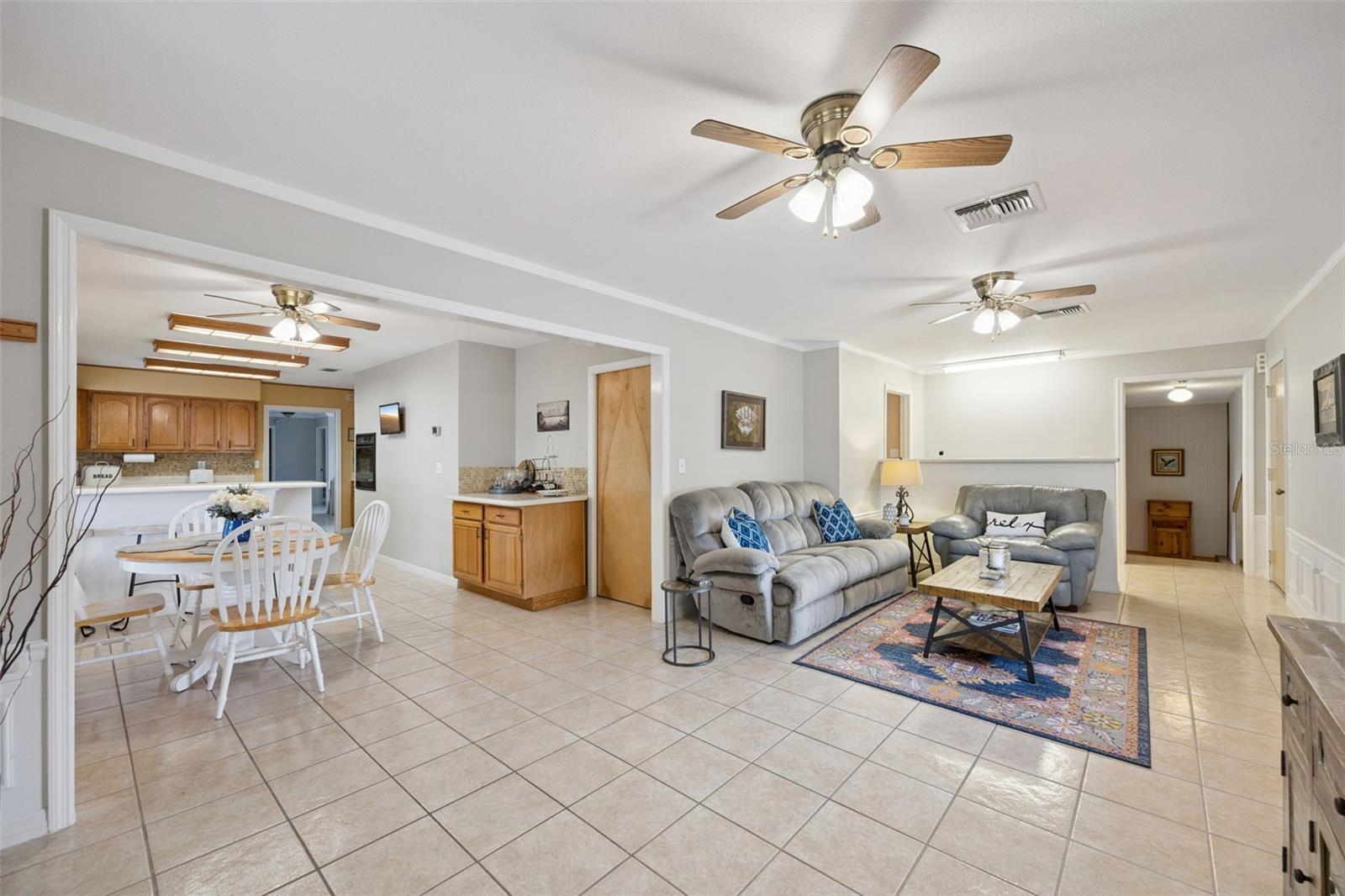 Open Concept Living & Breakfast Area: Bright open layout connecting the main living room to the casual dining nook and kitchen area, framed by easy-care tile floors.