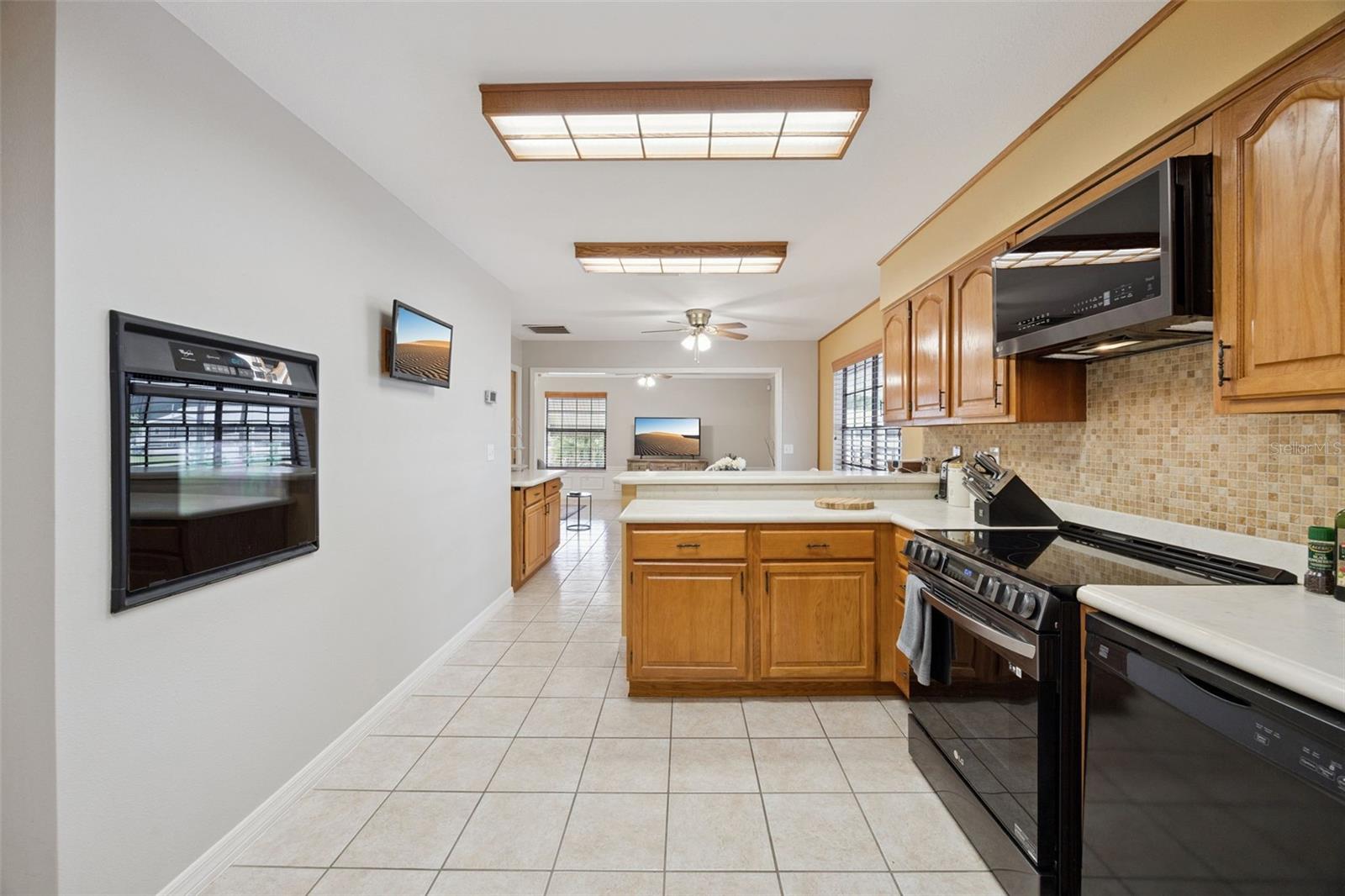 Kitchen Cooktop & Built-In Oven: View of the efficient kitchen workspace highlighting the smooth cooktop range, built-in wall oven, and upper overhead lighting.