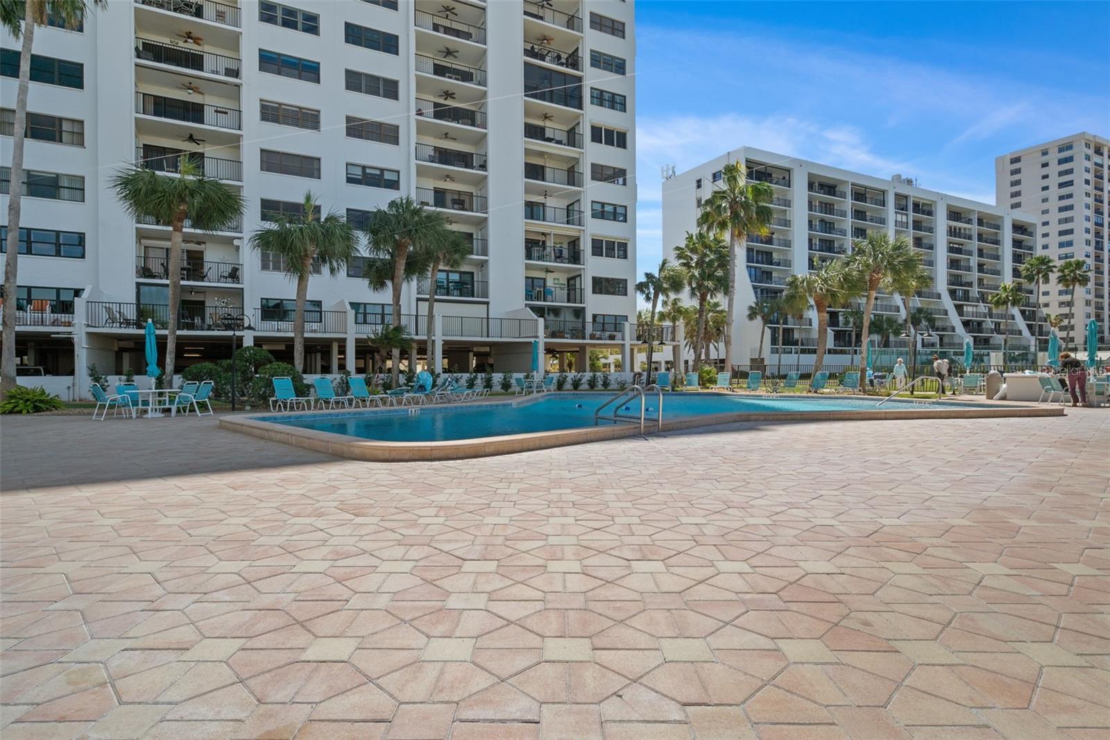 Spacious pool deck with plenty of table, chairs and chaise lounges around the refreshing pool!