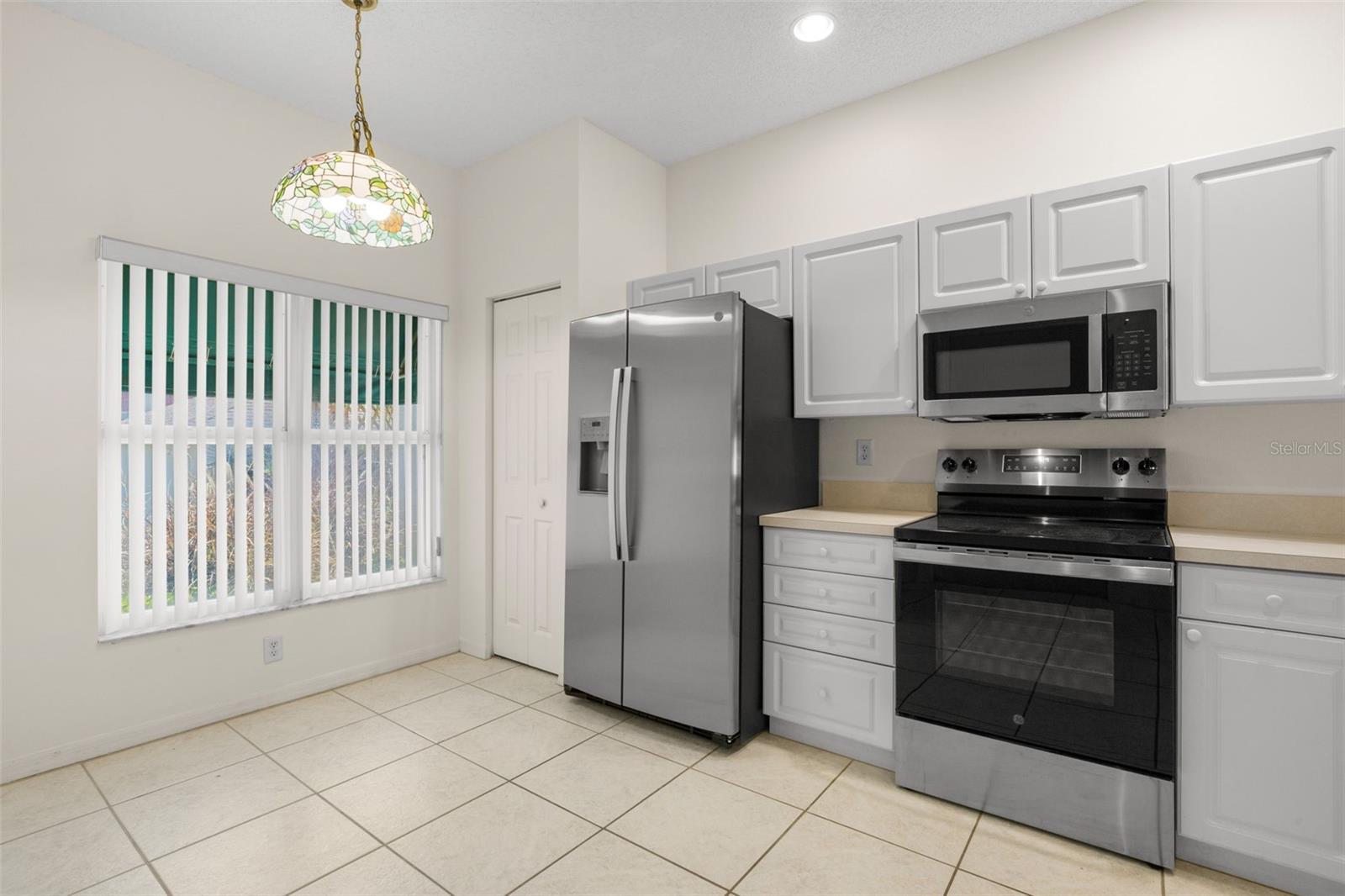 Spacious eat-in kitchen featuring ample cabinetry, generous counter space, and a dedicated dining area beneath a decorative pendant light. Spacious eat-in kitchen featuring ample cabinetry, generous counter space, and a dedicated dining area beneath a decorative pendant light.