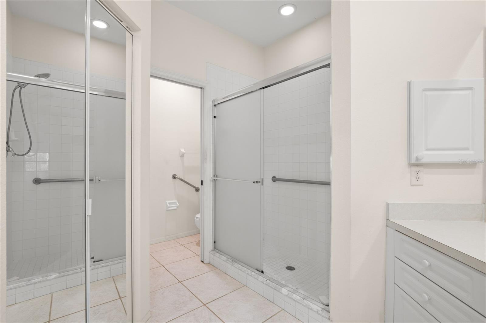 Walk-in closet and walk-in shower with sliding glass doors and tile surround, offering a clean, functional design. Private water closet.