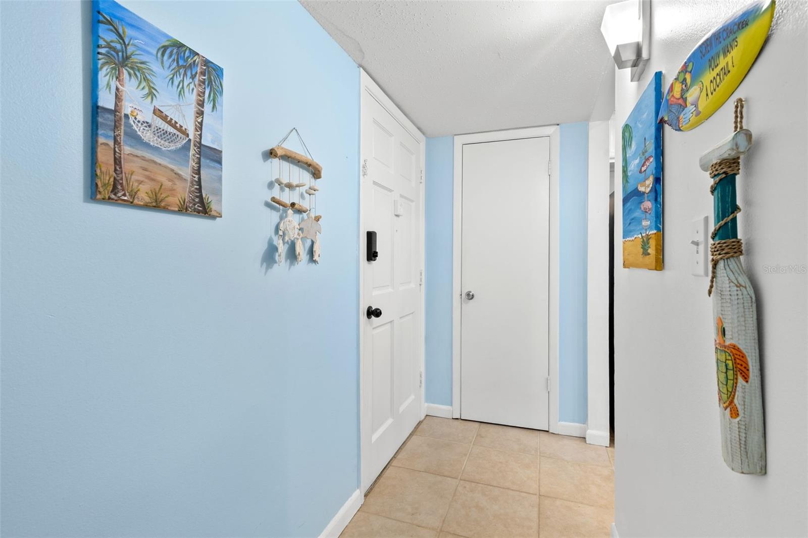The tiled foyer creates a defined entry into the condo, with the front door opening to a compact hall that leads directly toward the kitchen and main living areas.