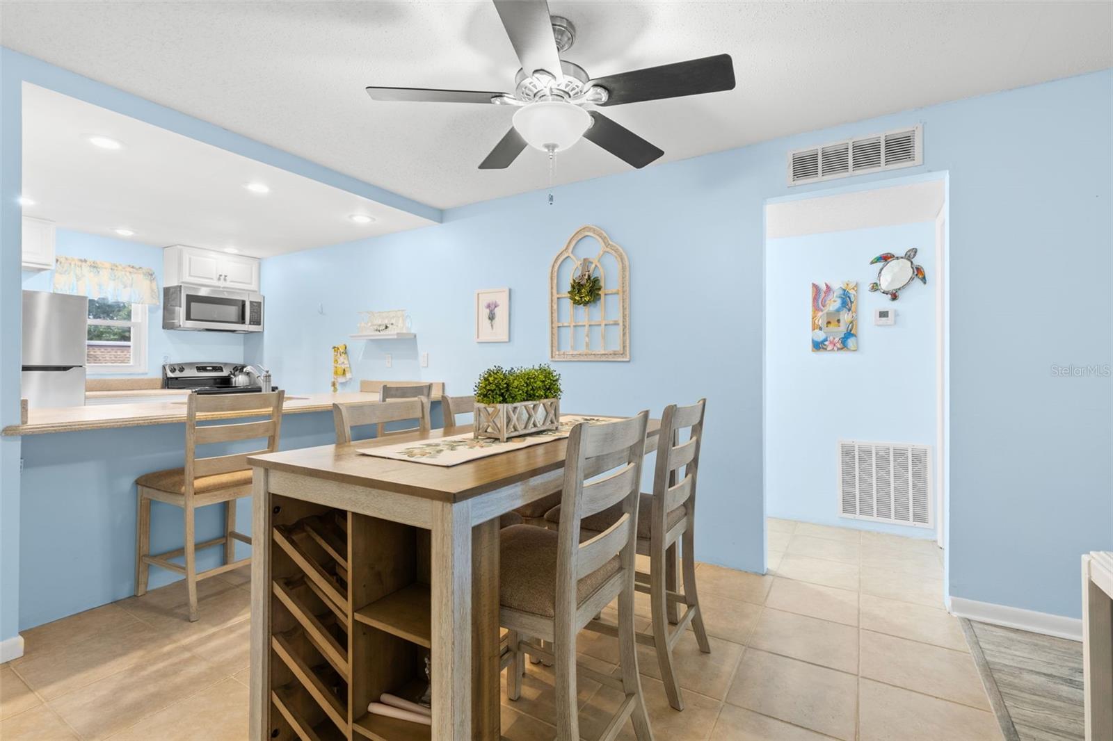 The dining area sits between the kitchen and bedroom hallway, with tile flooring, a ceiling fan and the breakfast bar just steps away for additional seating.
