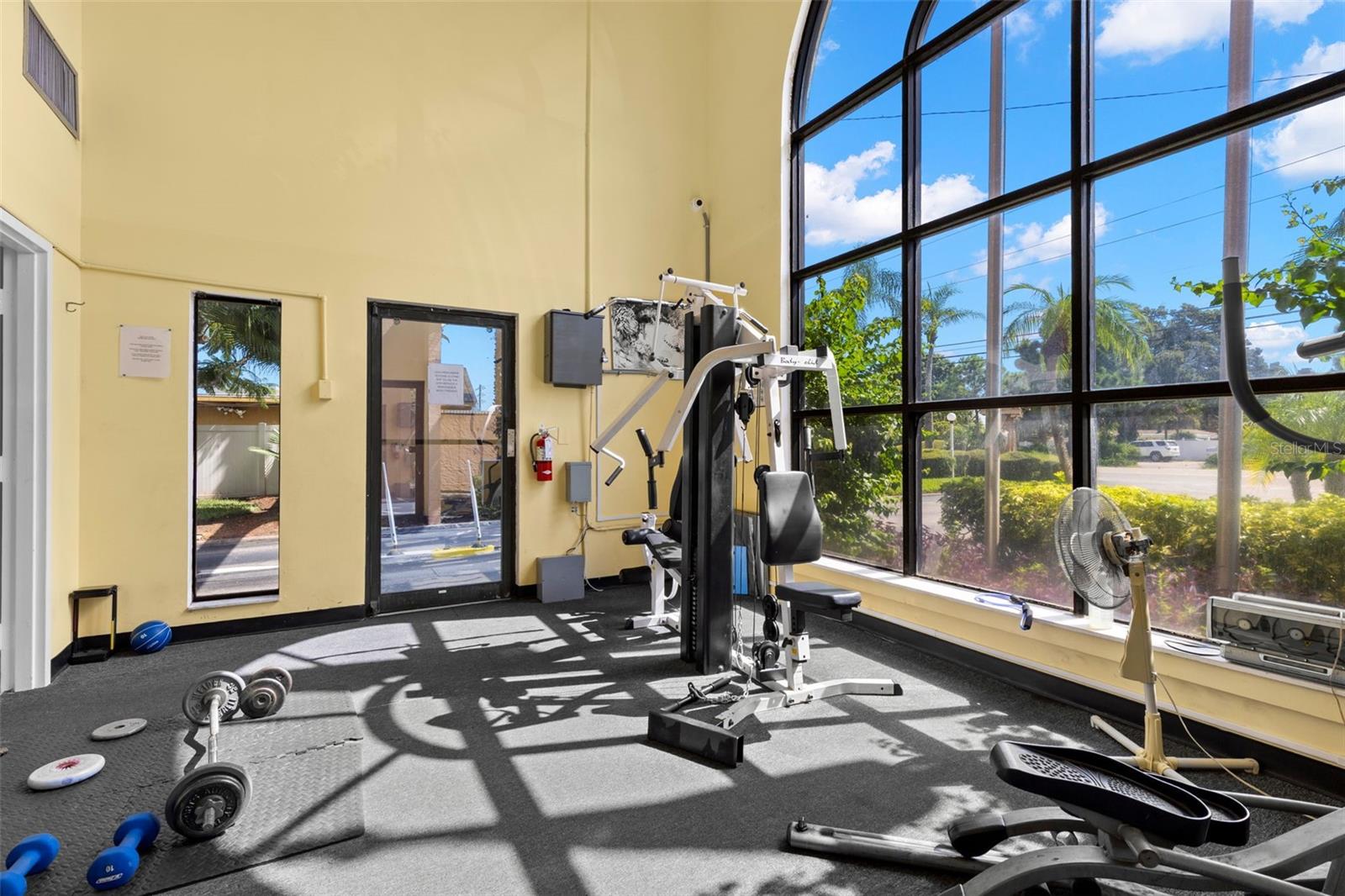 Tall arched windows fill the fitness center with natural light, while open floor space and a mix of strength-training equipment add flexibility to the community workout area.