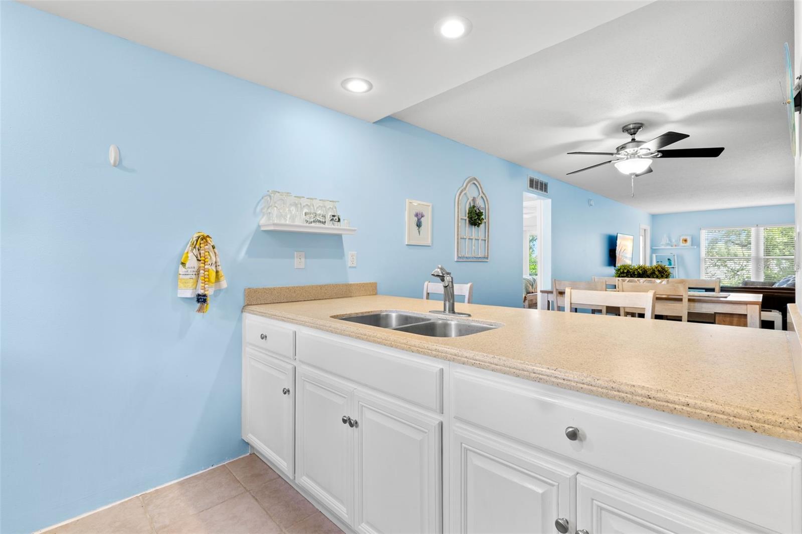 A long Corian breakfast bar extends the kitchen toward the dining and living areas, pairing generous counter space with a double-basin sink while keeping the room visually connected to the main living space.