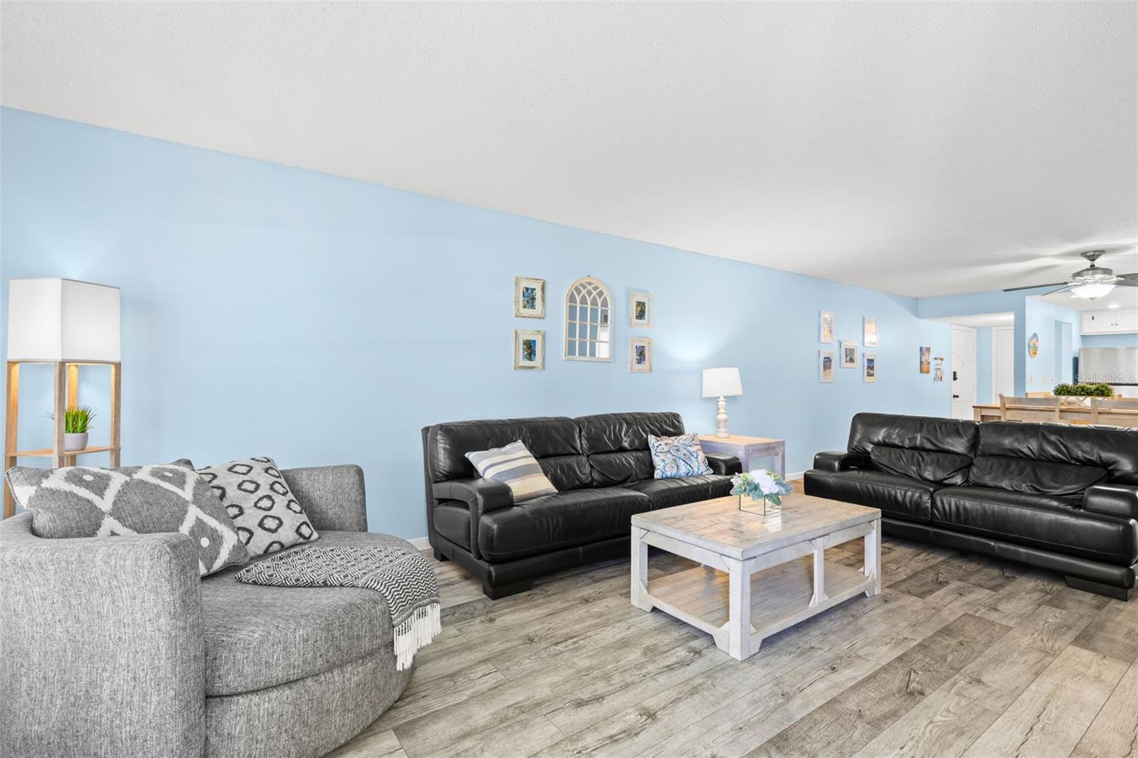 Looking back toward the dining area and kitchen, the living rooms generous proportions become even clearer, with luxury vinyl flooring, multiple seating areas and an open sightline that carries through the main living space.