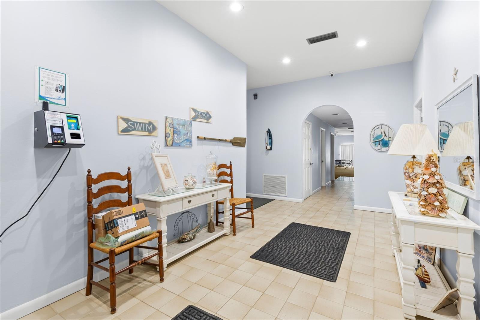 The clubhouse entry hall is finished with tile flooring and recessed lighting, with a welcoming coastal theme and easy access to the communitys gathering and recreation spaces beyond.