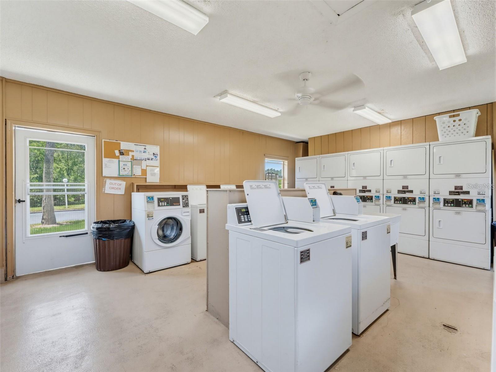The community laundry room is equipped with multiple washers and dryers, providing a convenient shared option for residents within New Atlantis Club.